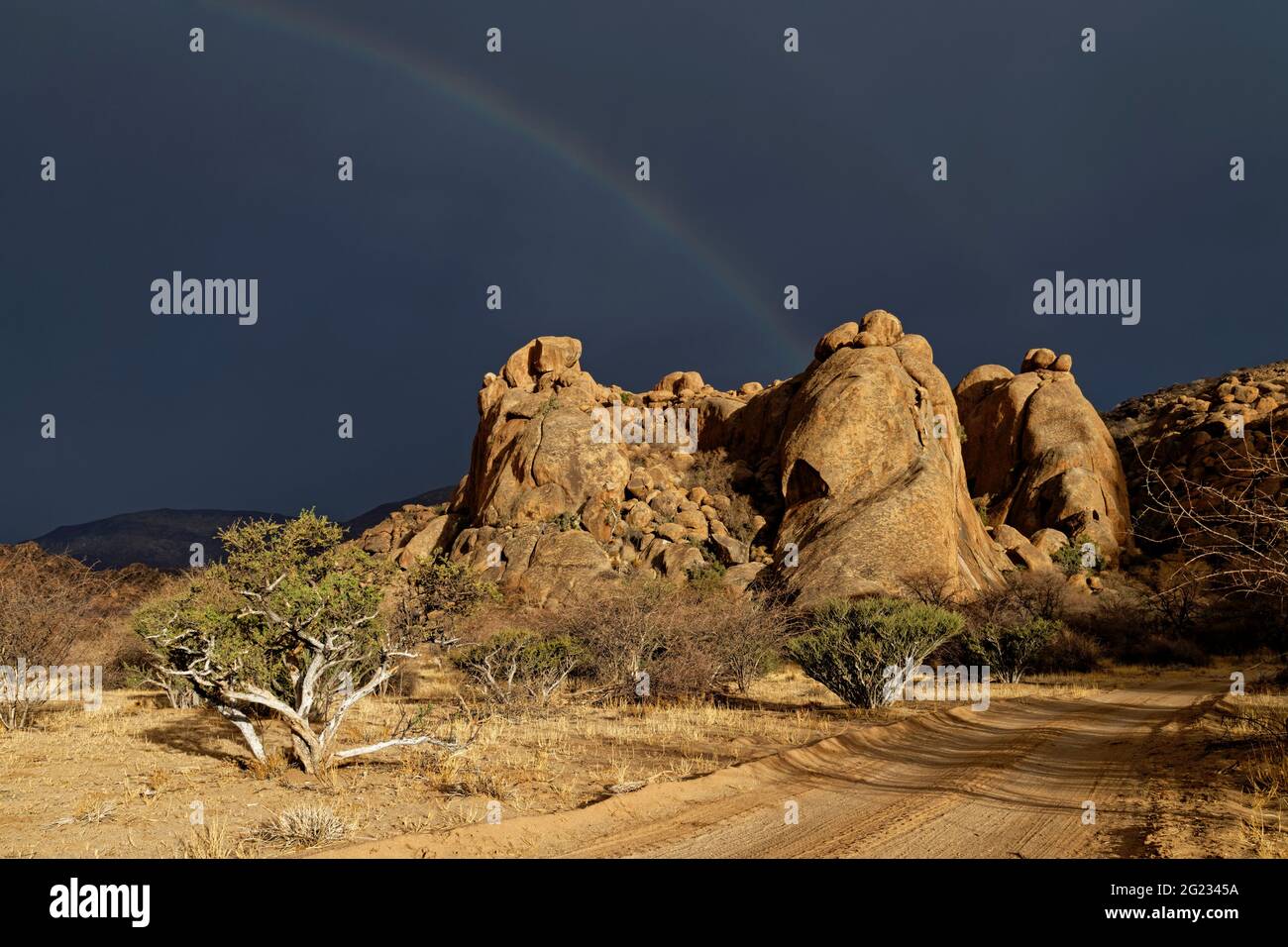 Guest farm Omandumba in the Erongo Mountains: Rain clouds and rainbow over rock formation 'Three Elephants', near Omaruru, Erongo Region, Namibia Stock Photo