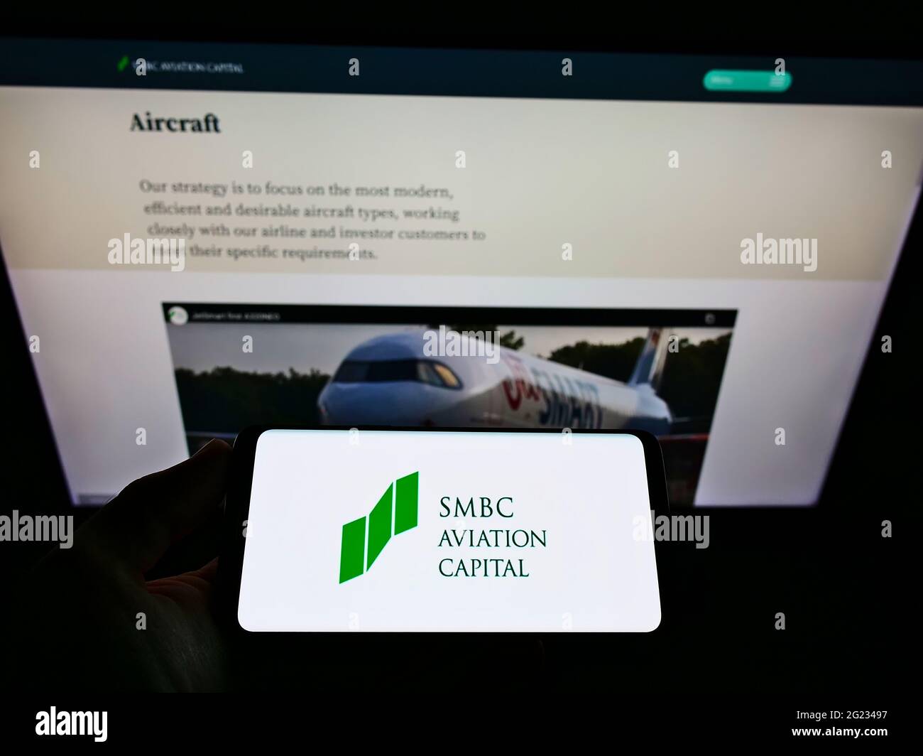 Person holding smartphone with logo of aircraft leasing company SMBC Aviation Capital on screen in front of website. Focus on phone display. Stock Photo