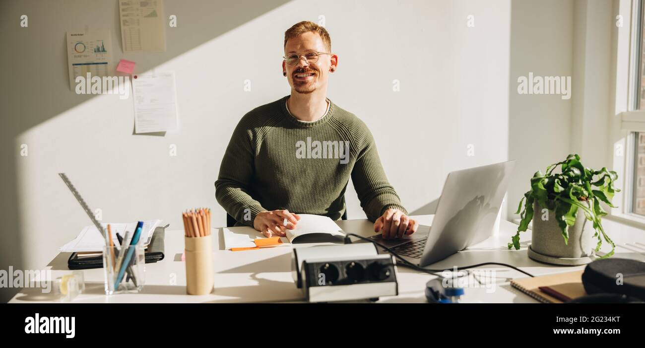 Creative entrepreneur sitting in his office wokring on a project on his laptop. Small business owner working independently. Stock Photo