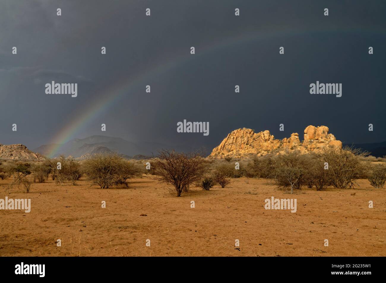 Guest farm Omandumba in the Erongo Mountains: Rainbow and rain clouds over a rock formation (granite), rainy season,  Erongo Region, Namibia Stock Photo