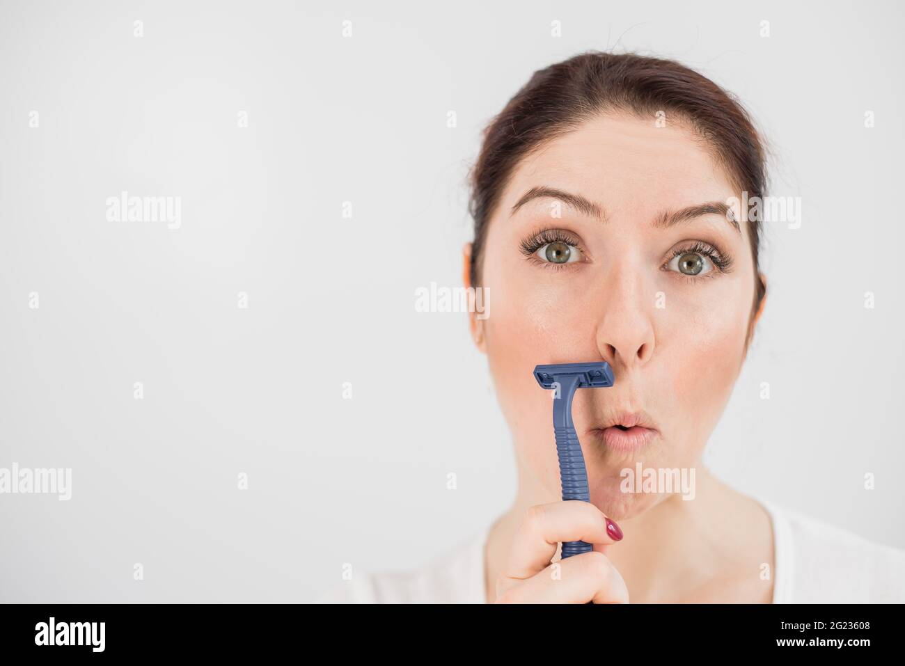 Woman With Straight Razor Caucasian funny woman shaves her face with a straight razor on a white ...