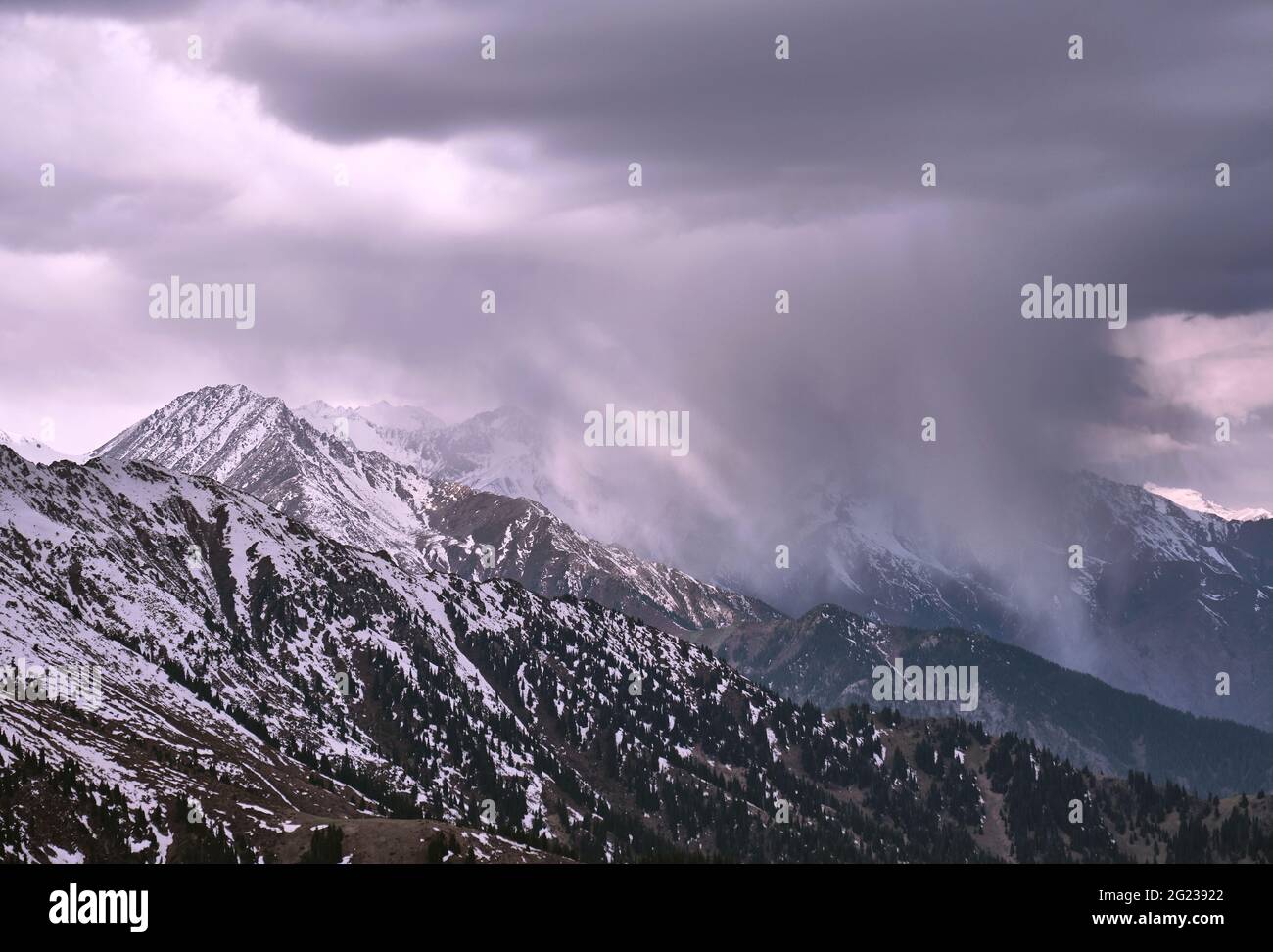 Spectacular snow clouds in a mountain gorge illuminated by the soft light of the morning sun; amazing natural phenomena, worsening weather, the approa Stock Photo