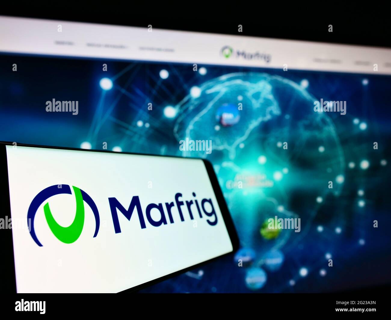 Smartphone with logo of Brazilian food company Marfrig Global Foods S.A. on screen in front of website. Focus on center-left of phone display. Stock Photo