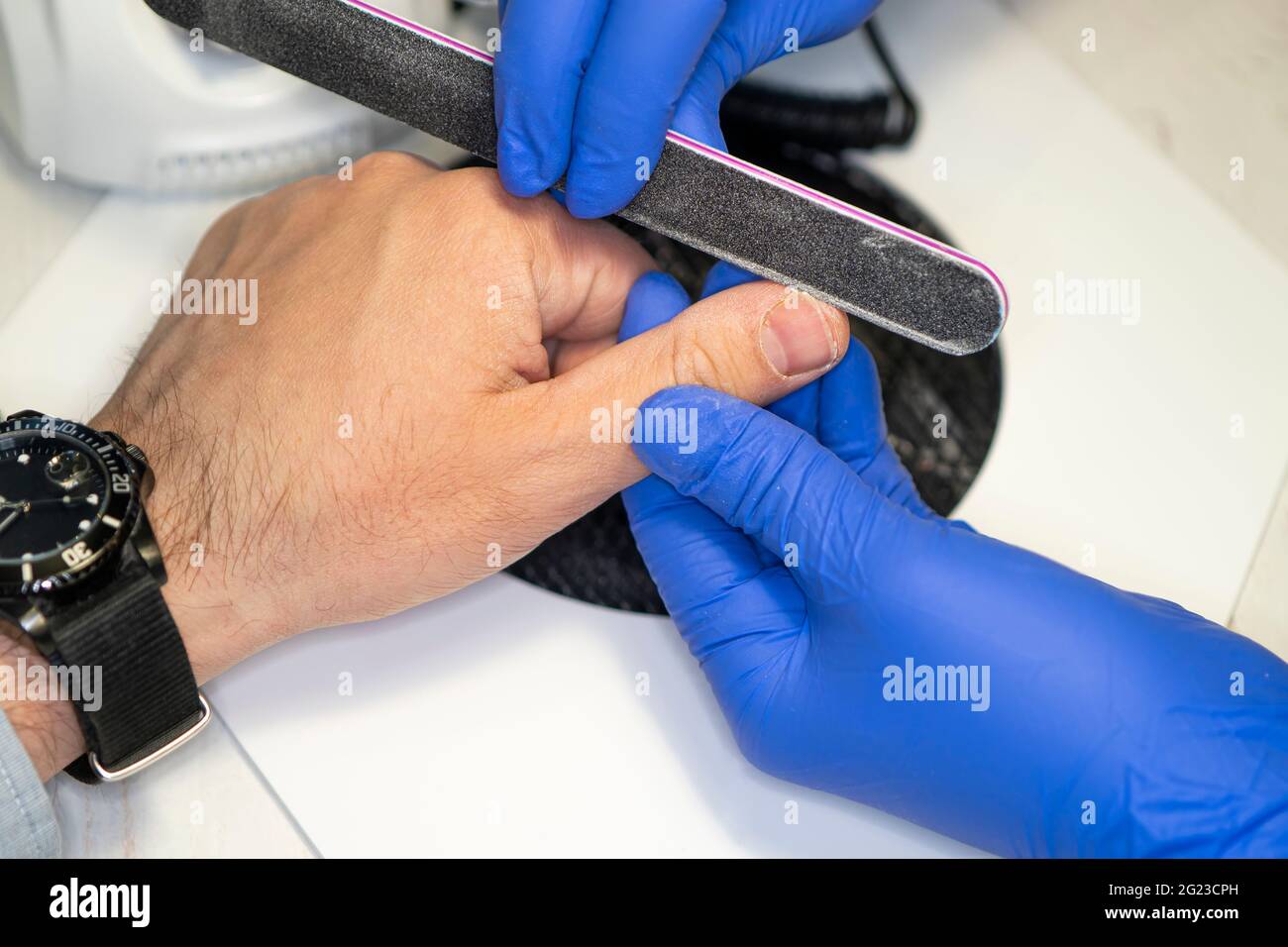 a man's hand on the manicure procedure. Manicurist filing man's nails
