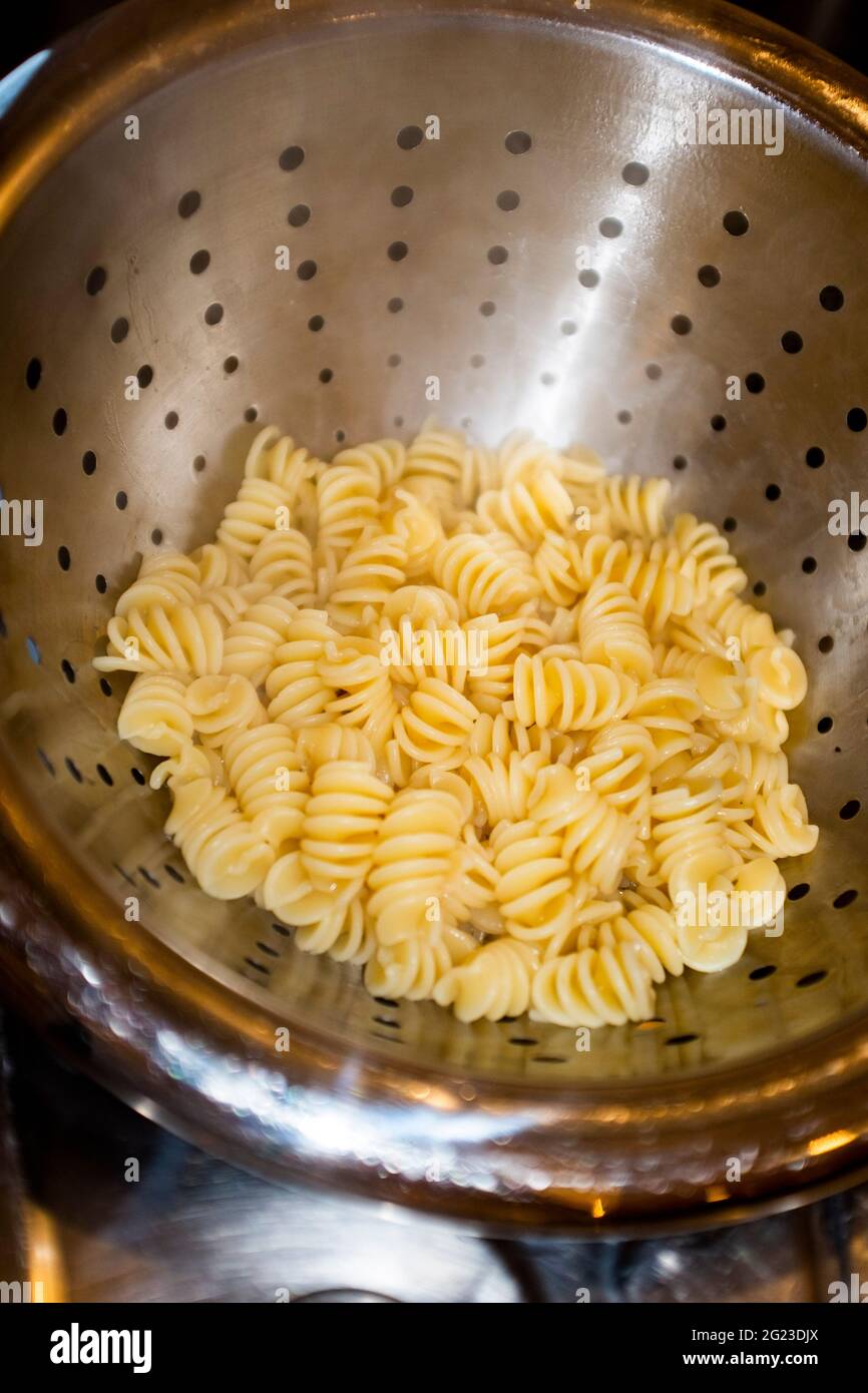 Cooking dried pasta shapes in boiling water and draining Stock Photo
