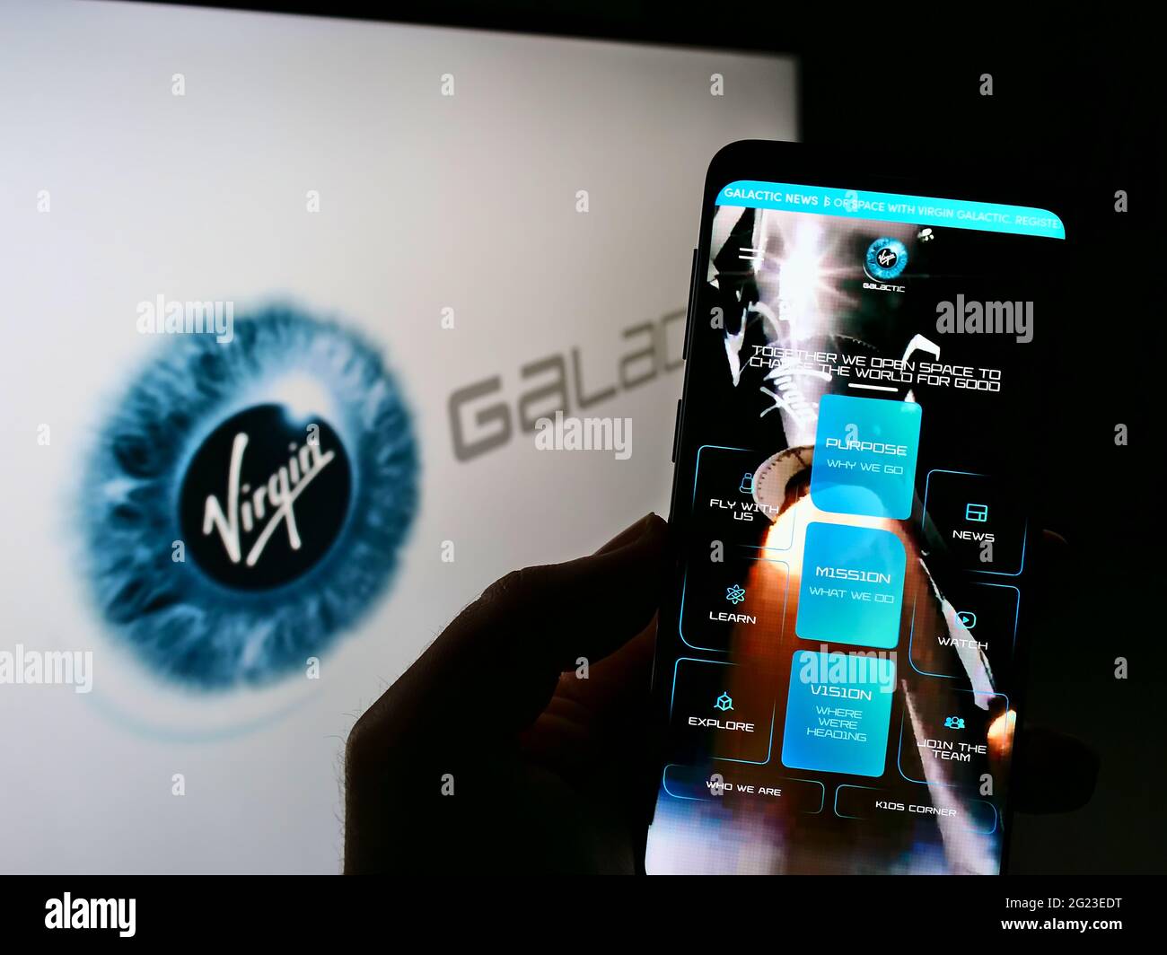 Person holding cellphone with webpage of US aerospace company Virgin Galactic LLC on screen in front of logo. Focus on center of phone display. Stock Photo