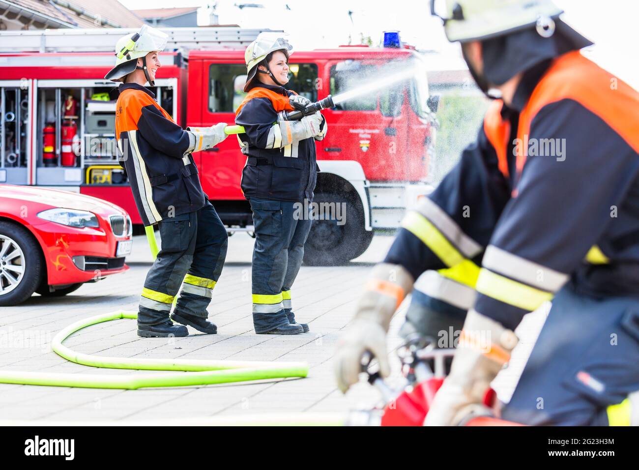Fire fighter connecting hoses in front of fire engine Stock Photo - Alamy
