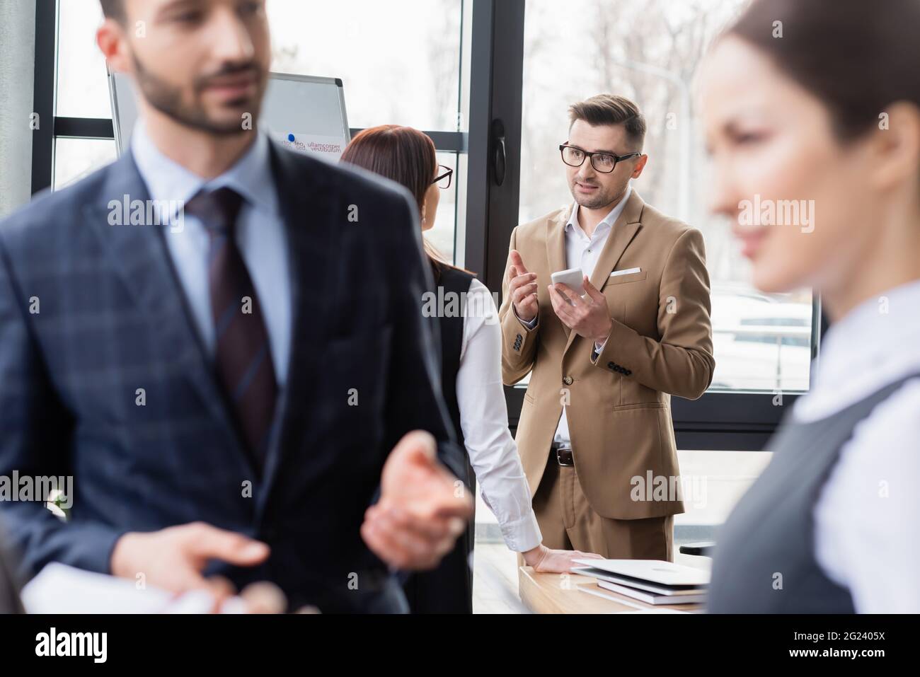 Pointing Near Businessman with smartphone pointing with finger near colleague in ...