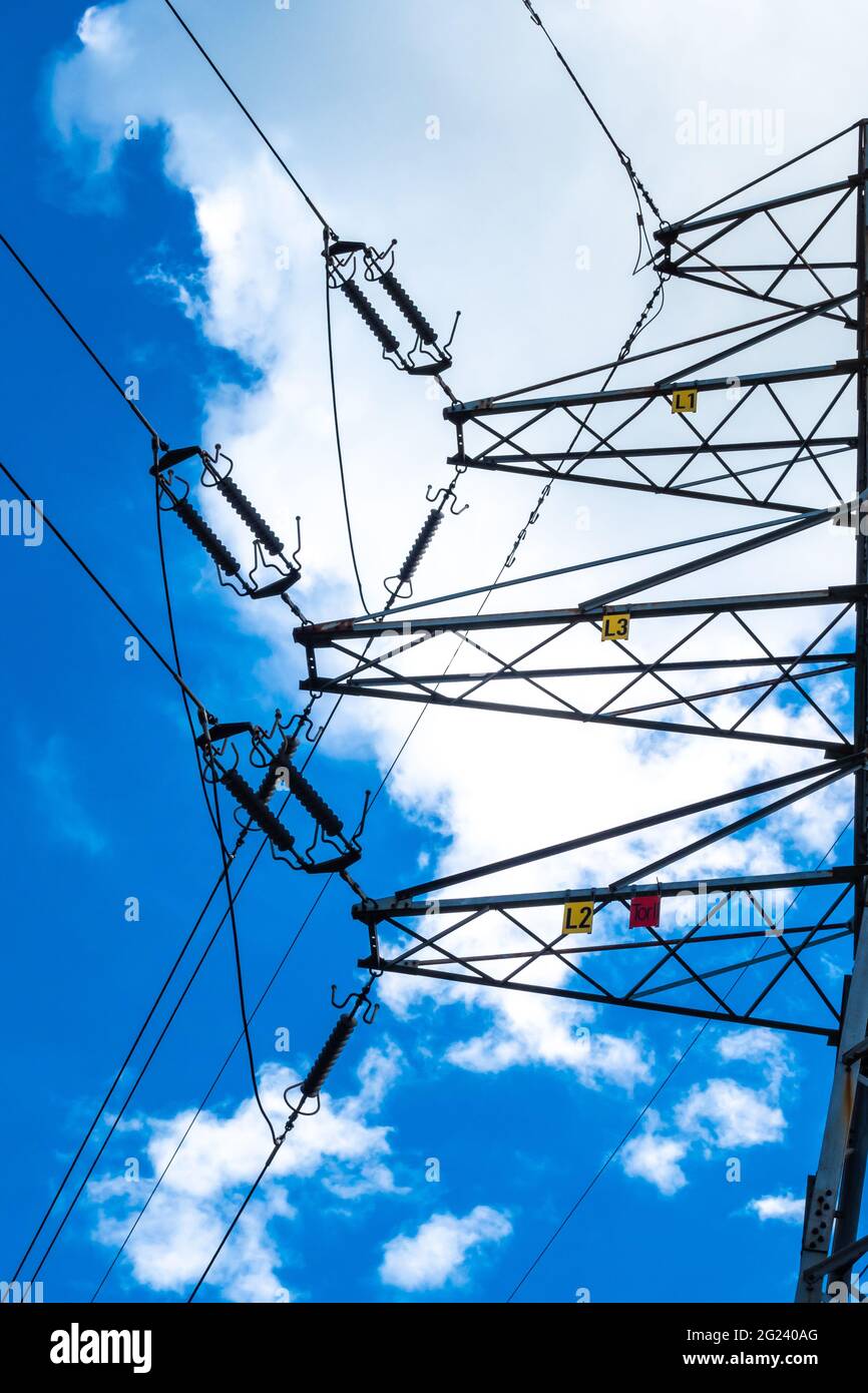 Electric pylons of high voltage lines against a blue sky with white clouds. Photo taken in daylight. Stock Photo