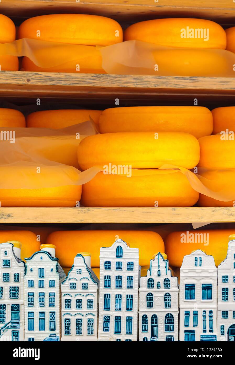 Dutch cheese ripening on wooden shelfs with Delft souvenir houses in front Stock Photo