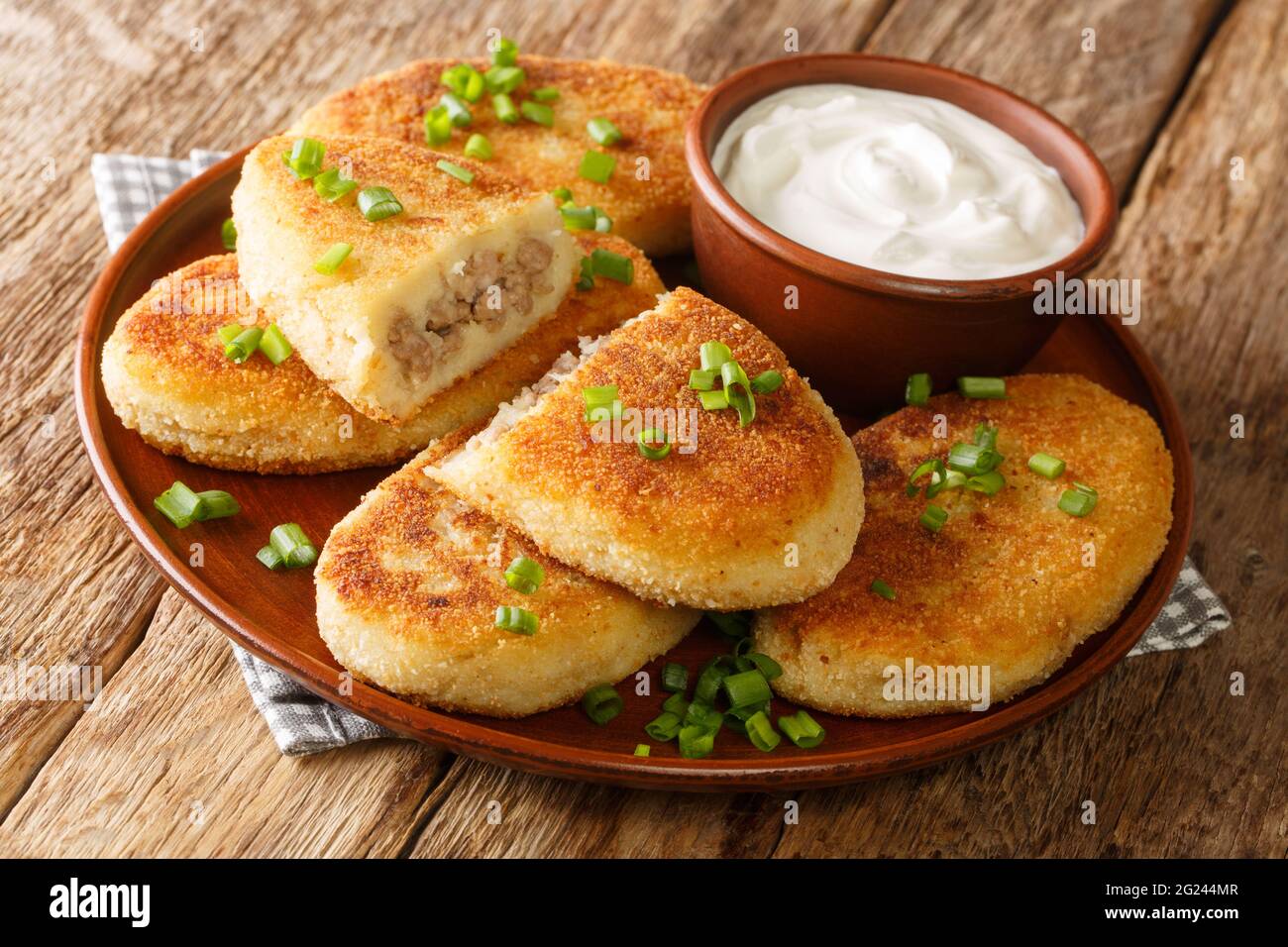Homemade hot potato zrazy pies with meat filling with sour cream close-up in a plate on the table. horizontal Stock Photo