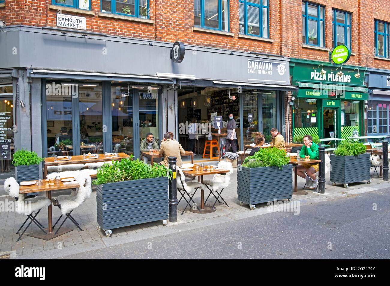 People sitting at tables outside Caravan restaurant at Exmouth Market street in Clerkenwell social distancing in London EC1 England UK  KATHY DEWITT Stock Photo