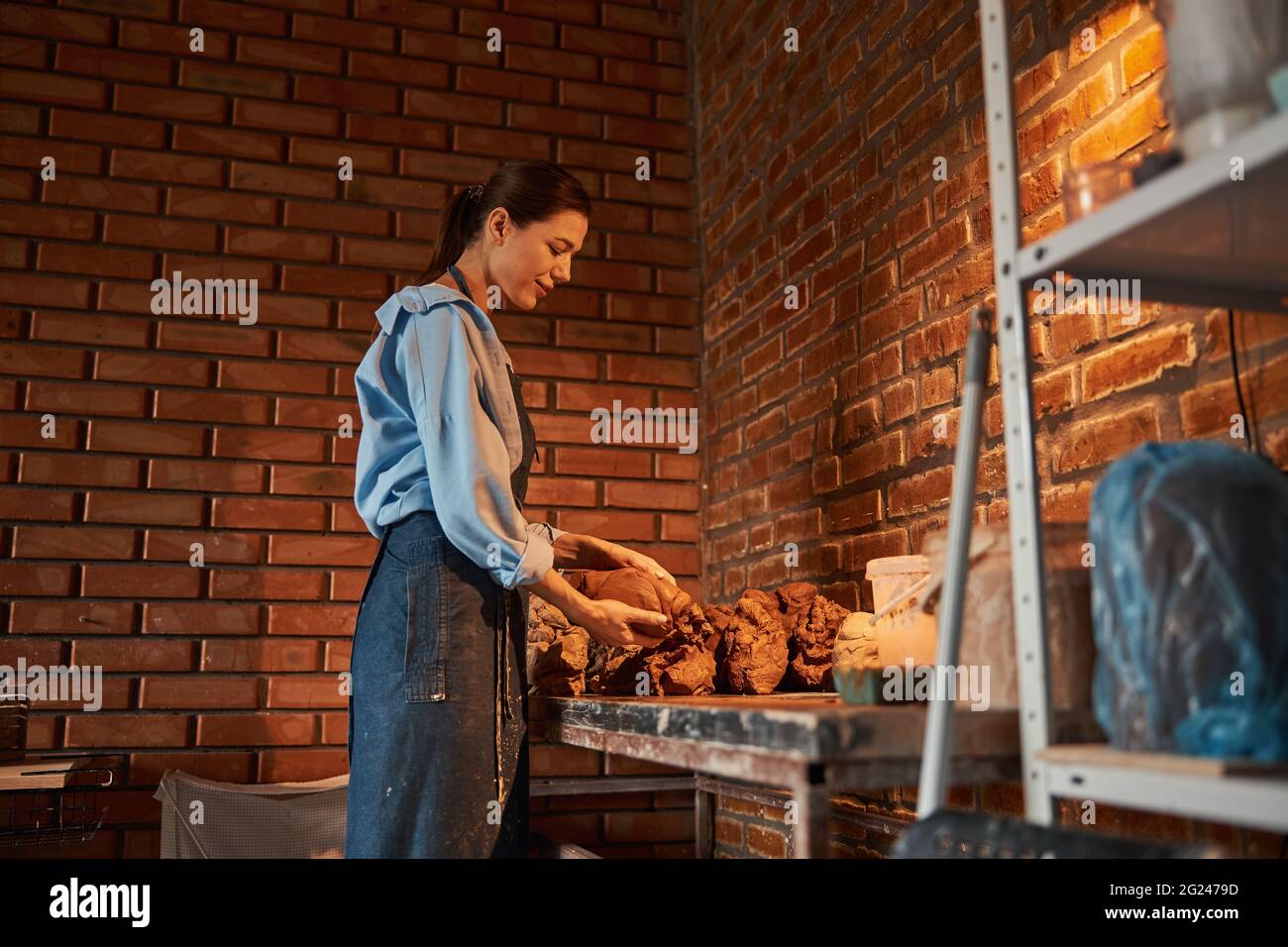 Happy smiling Caucasian female artisan making patterns with earthenware products in cozy home studio Stock Photo