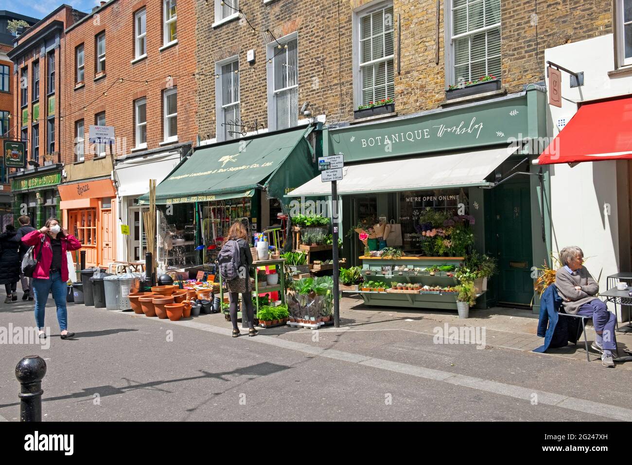 Woman wearing face mask and person looking at plants in Exmouth Market