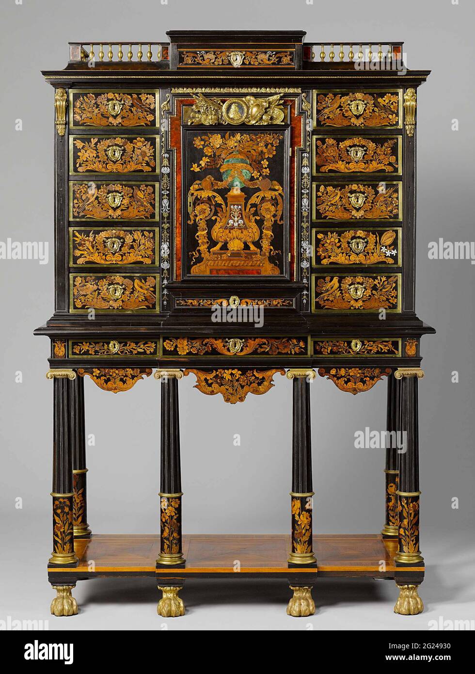 Cabinet. This may be the earliest-known masterpiece by Boulle, the most celebrated cabinetmaker of his time. Boulle perfected the technique of floral marquetry in various woods. The gilt-bronze armorial trophy above the middle door originally contained a portrait of Louis XIV. It was replaced with a likeness of King George I ofEngland (1660–1727). Stock Photo