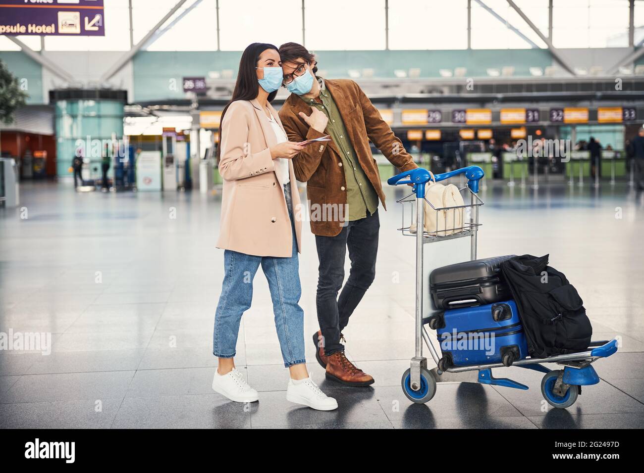 Young couple with luggage trolley walking down airport terminal Stock ...