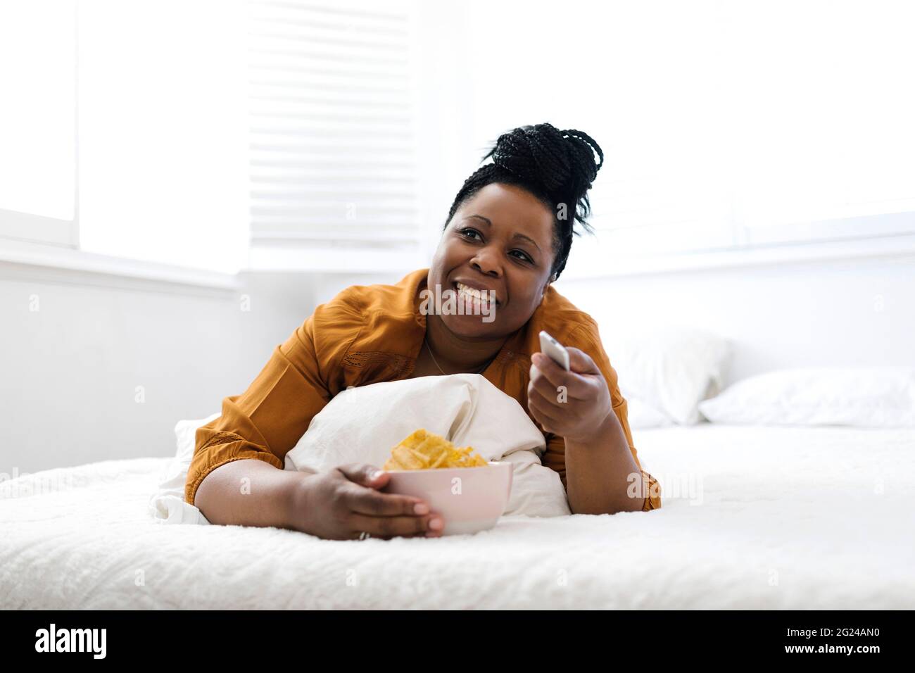 Woman eating potato chips in bed Stock Photo
