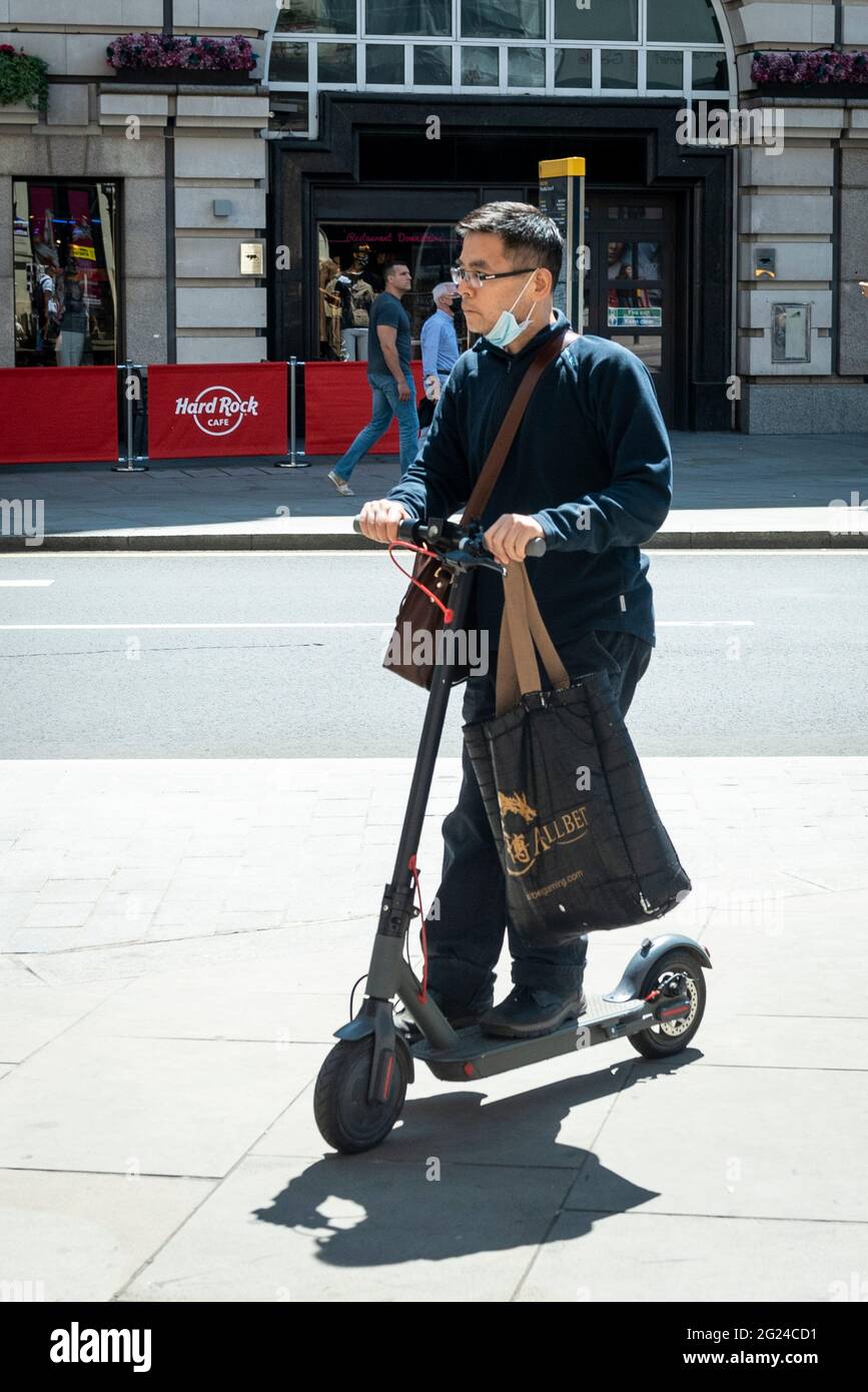 London, UK. 8 June 2021. A man rides his private electric scooter near  Piccadilly Circus. Currently, private electric scooters can only legally be  used in the UK on private land but are