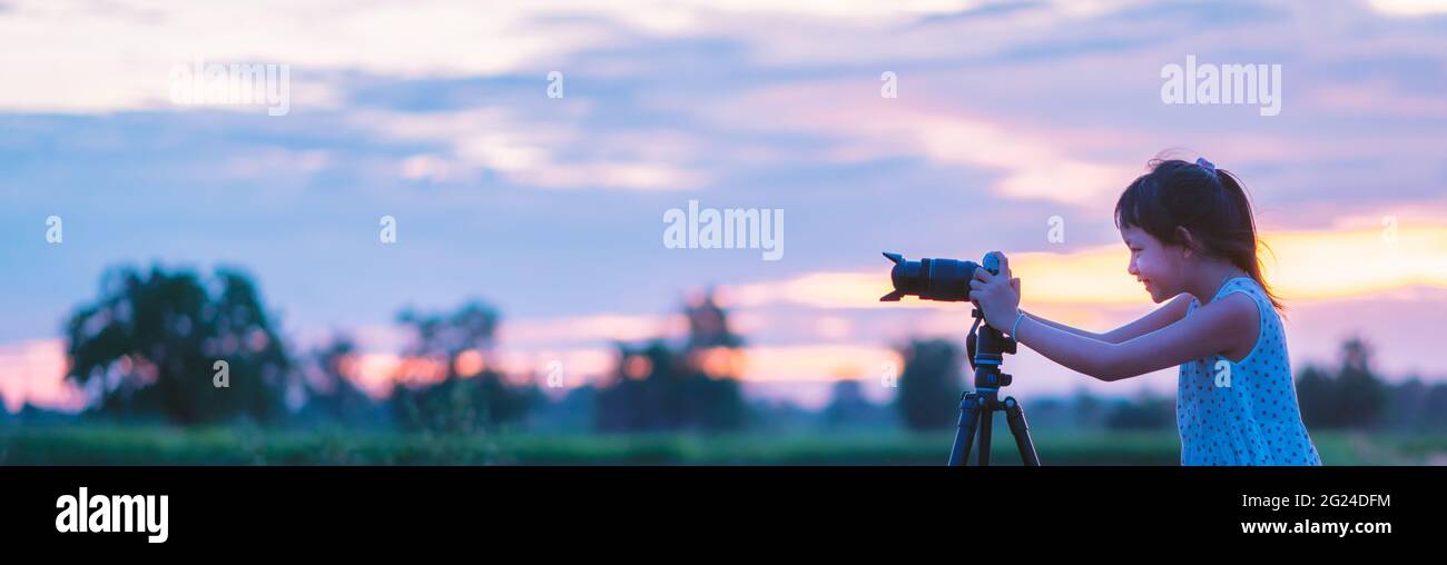 Smile little girl taking picture silhouette sunset sky by camera on tripod  standing with happy Stock Photo - Alamy