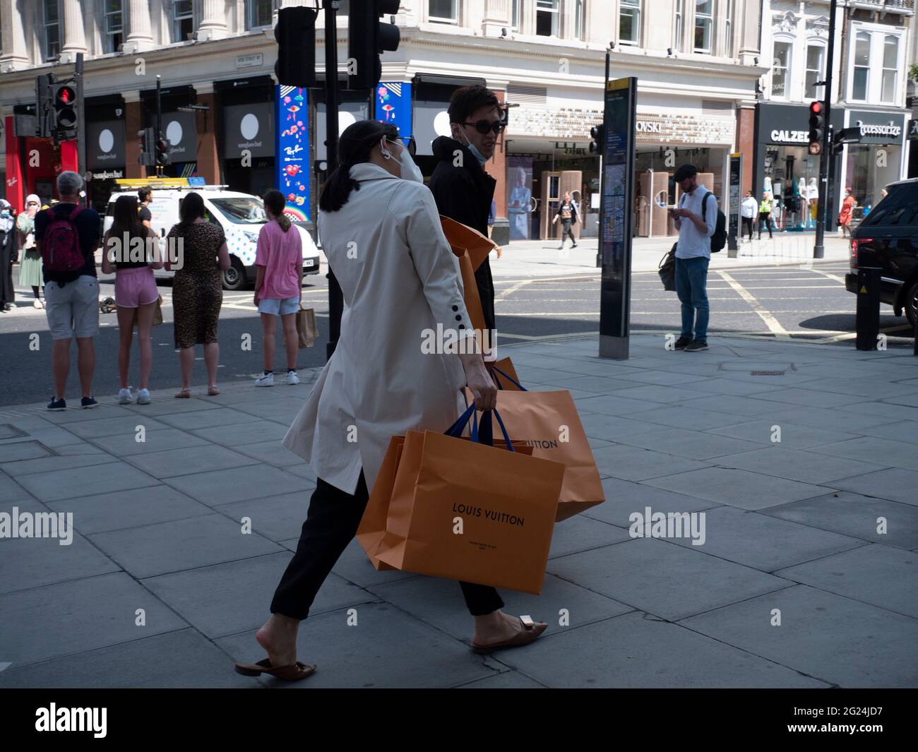 cache Postimpressionisme grådig Shoppers with Louis Vuitton bags in Oxford Street London, pass bus with  advert for fashion outlet boohoo Stock Photo - Alamy