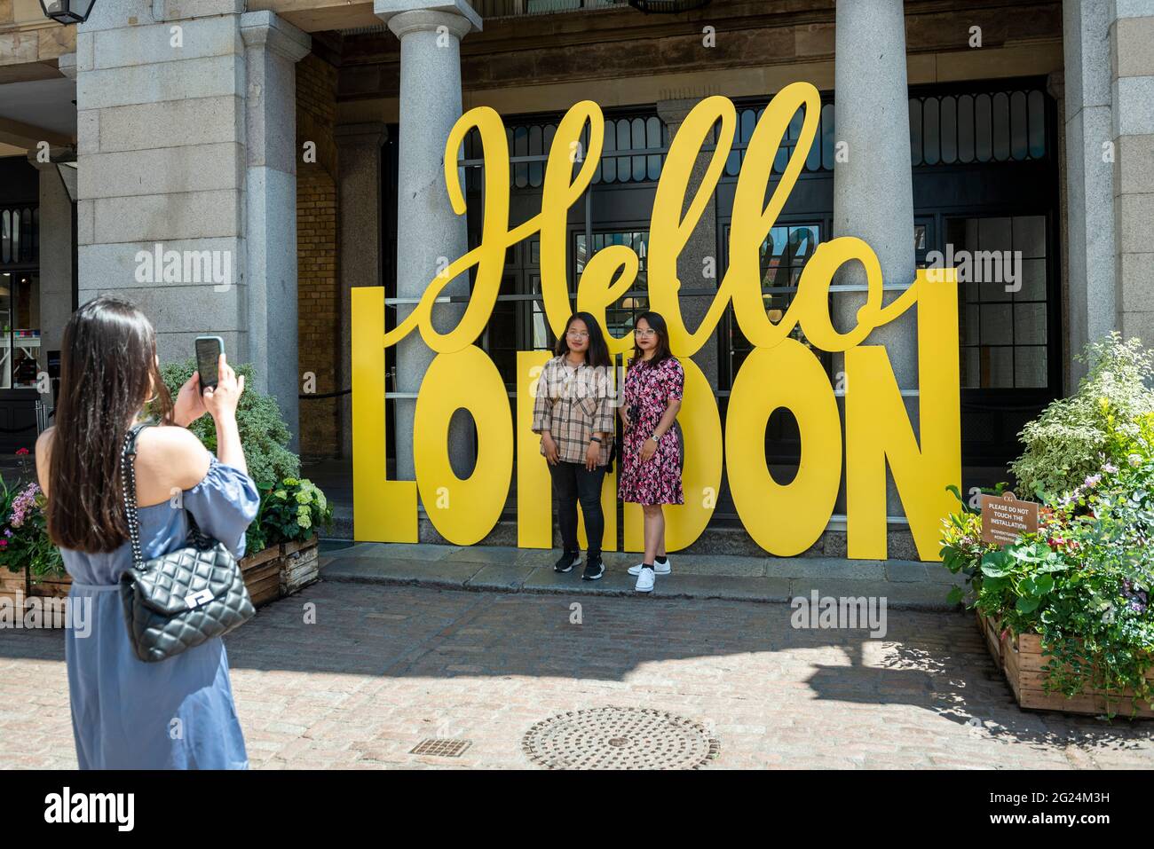 London, UK.  8 June 2021. Women take photos next to a Hello London sign in Covent Garden.  The area has experienced reduced footfall due to the ongoing pandemic.  Local shops and related businesses are hoping that the relaxation of lockdown restrictions on 21 June will lead to the return of tourists and shoppers.  Credit: Stephen Chung / Alamy Live News Stock Photo