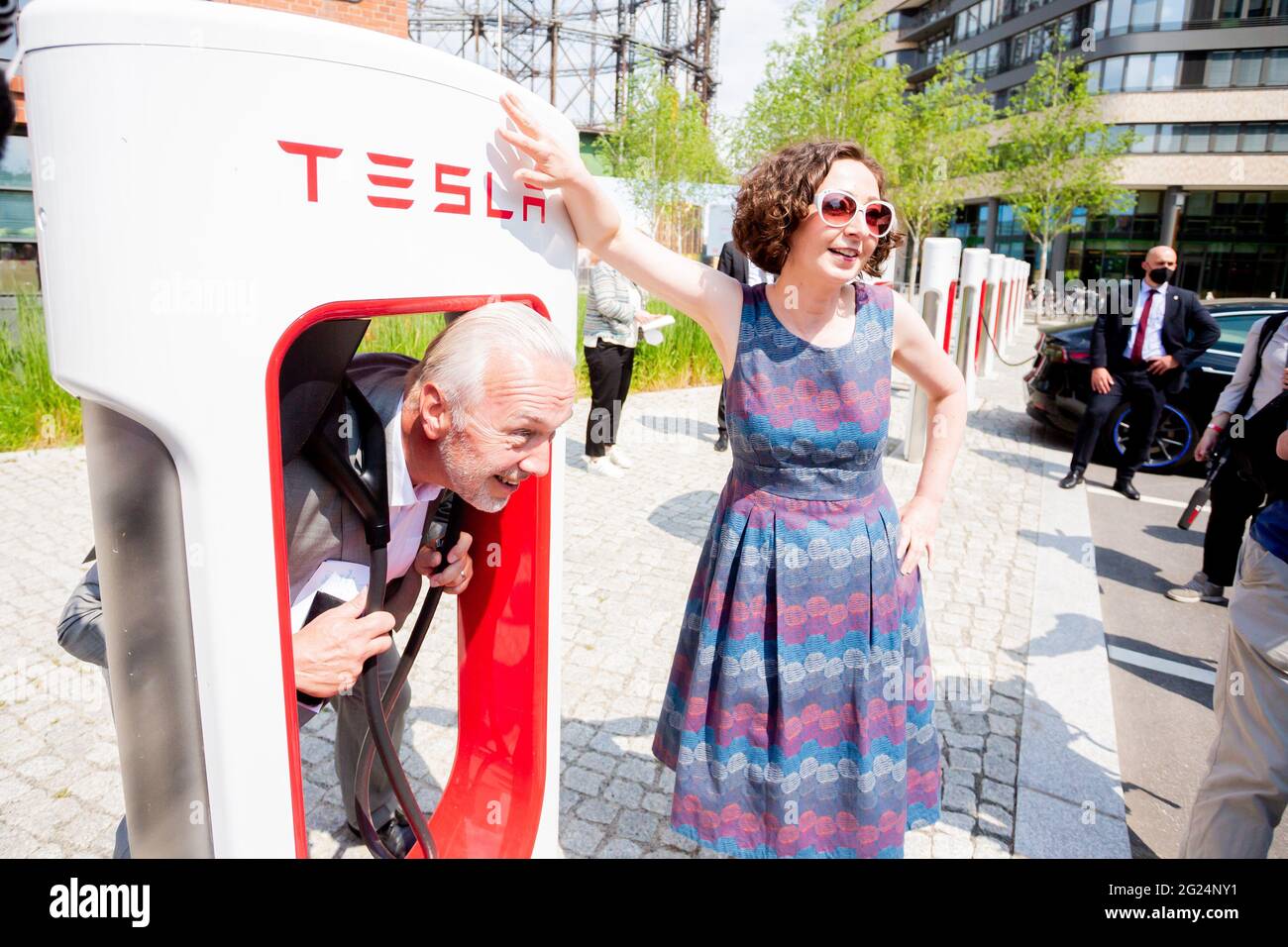 Berlin, Germany. 08th June, 2021. Reinhard Müller, CEO of EUREF AG, sticks his head through a Tesla Supercharger next to Ramona Pop (Bündnis 90/Die Grünen), Berlin's Senator for Economic Affairs, during a tour of the EUREF Campus site at Gasometer Schöneberg. The Berlin Senate held its meeting today at Schöneberg Town Hall, after which individual members of the Senate will embark on a district tour. Credit: Christoph Soeder/dpa/Alamy Live News Stock Photo