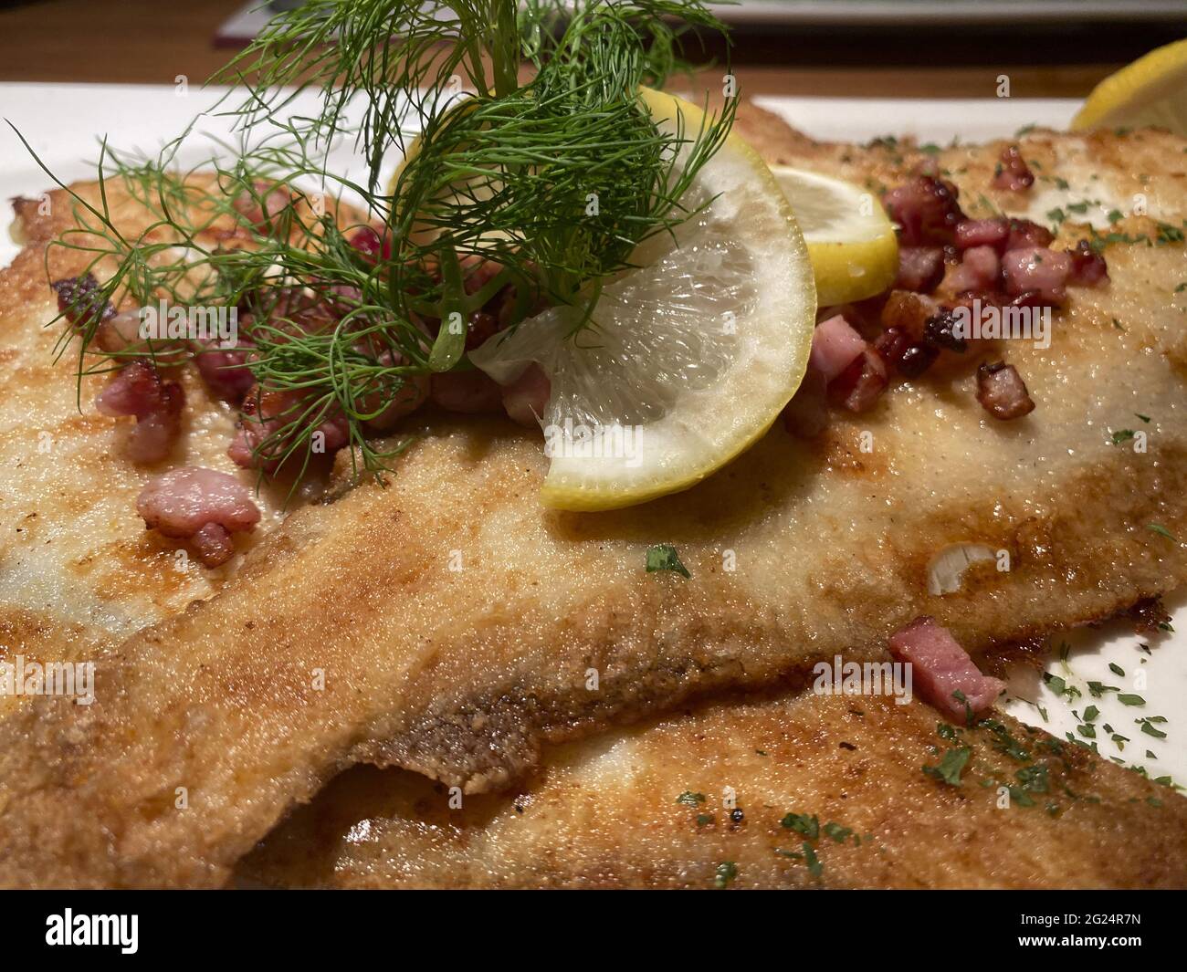 Frisch gebratene und panierte Scholle mit Speck, Zitrone und Dill.Freshly fried and breaded plaice with bacon, lemon and dill. Stock Photo