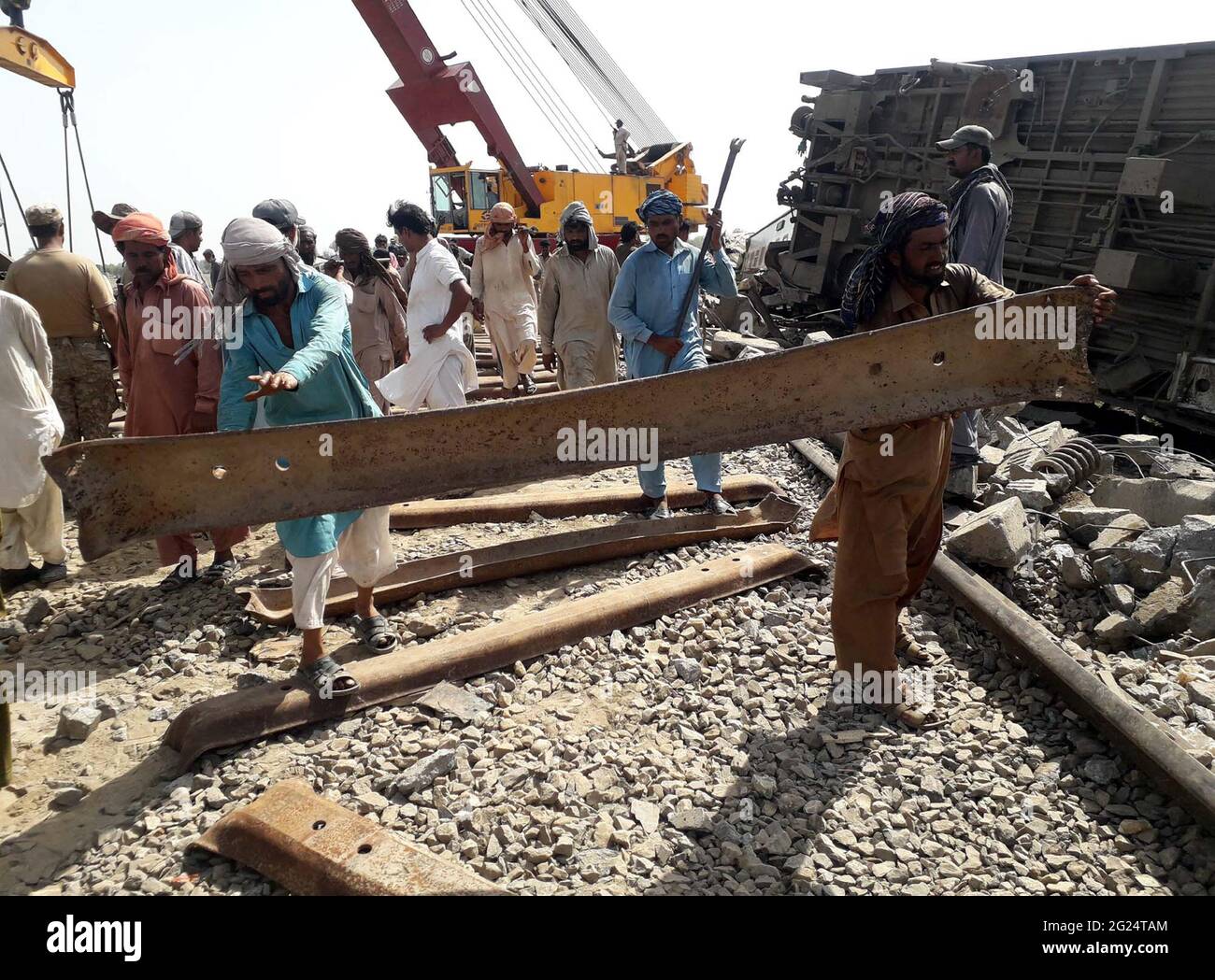 Heavy machinery and laborers are busy in removing a derailed trains and mending works main stream track of Pakistan Railways after accident between two trains on yesterday, in Ghotki on Tuesday, June 08, 2021. The Ghotki train accident took place after a track's welding joint broke, causing the Millat Express train to crash onto a down track, says an initial investigation report into the crash. At least 50 people were killed and over 100 injured during the wee hours of Monday when Sir Syed Express and the Millat Express collided in Pakistan's Dharki town near the Mirpur Mathello Station. Stock Photo