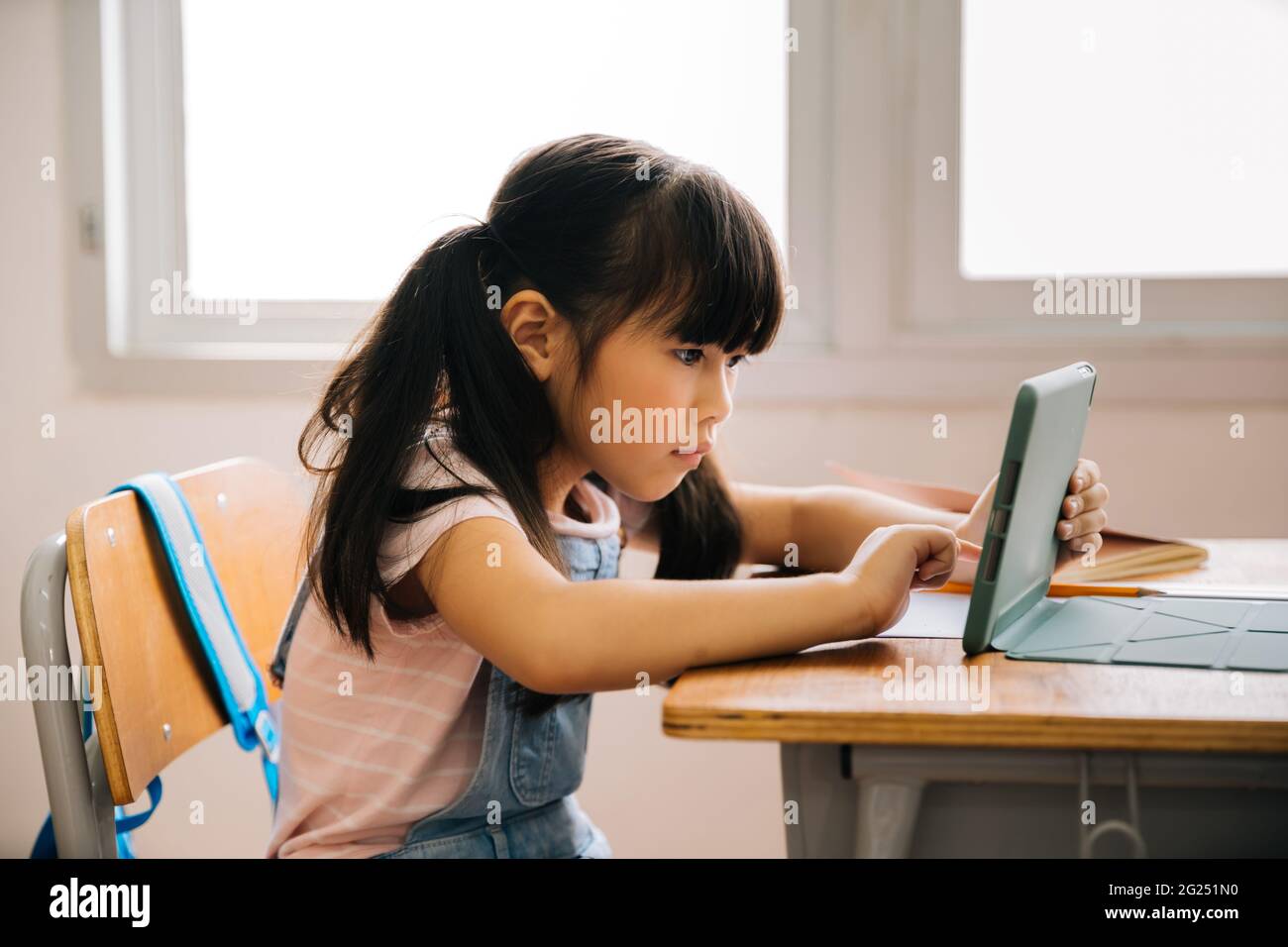 Asian school girl using digital device in school classroom, digital