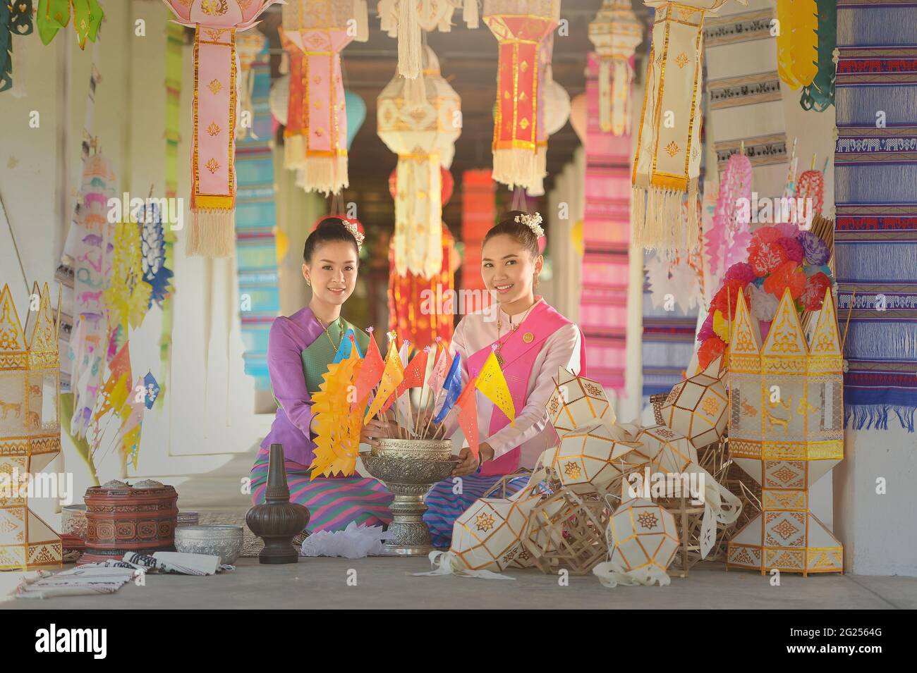 Portrait of two women in traditional Thai clothing sitting amongst lanterns, Thailand Stock Photo