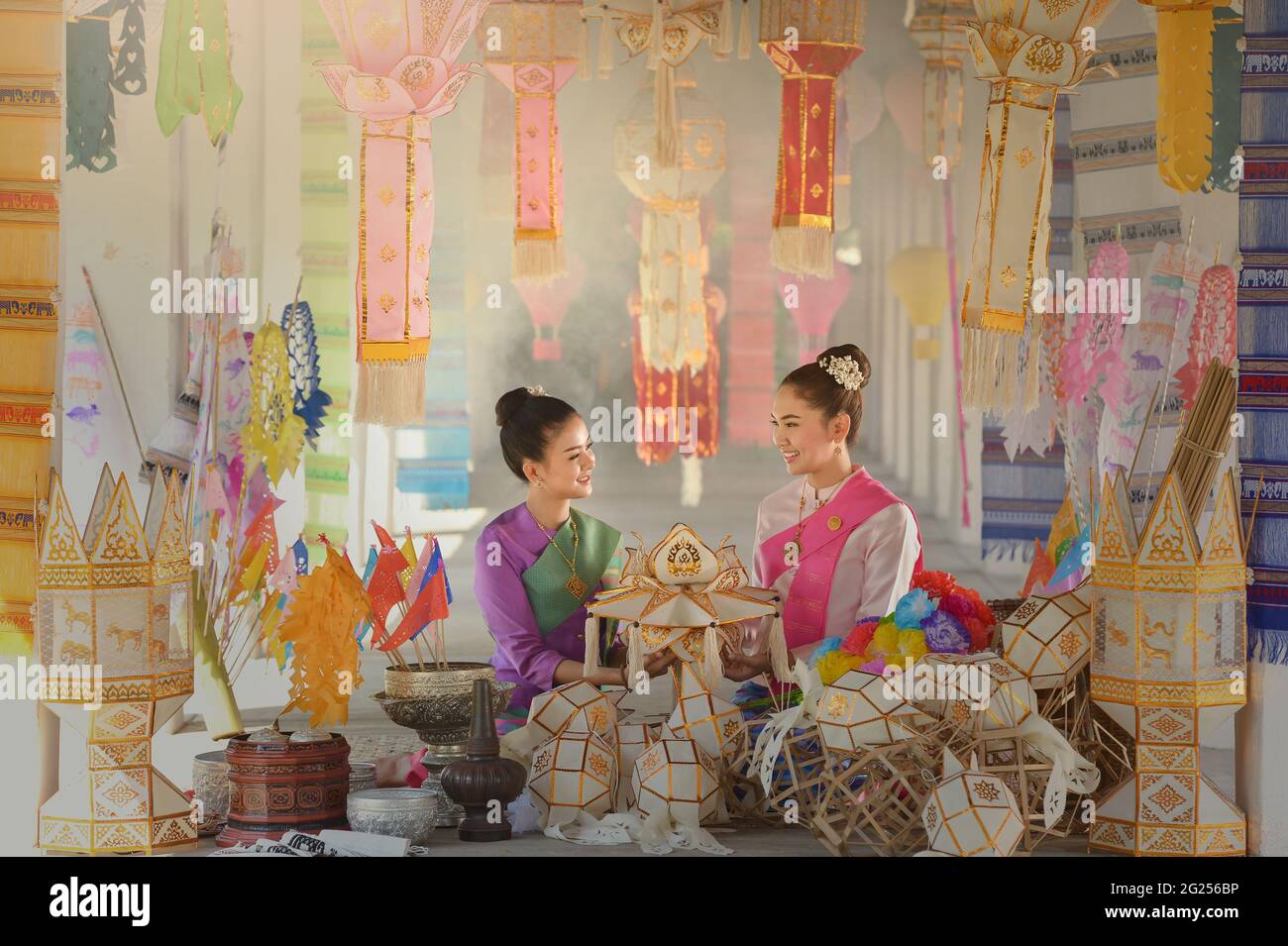 Portrait of two women in traditional Thai clothing sitting amongst lanterns, Thailand Stock Photo
