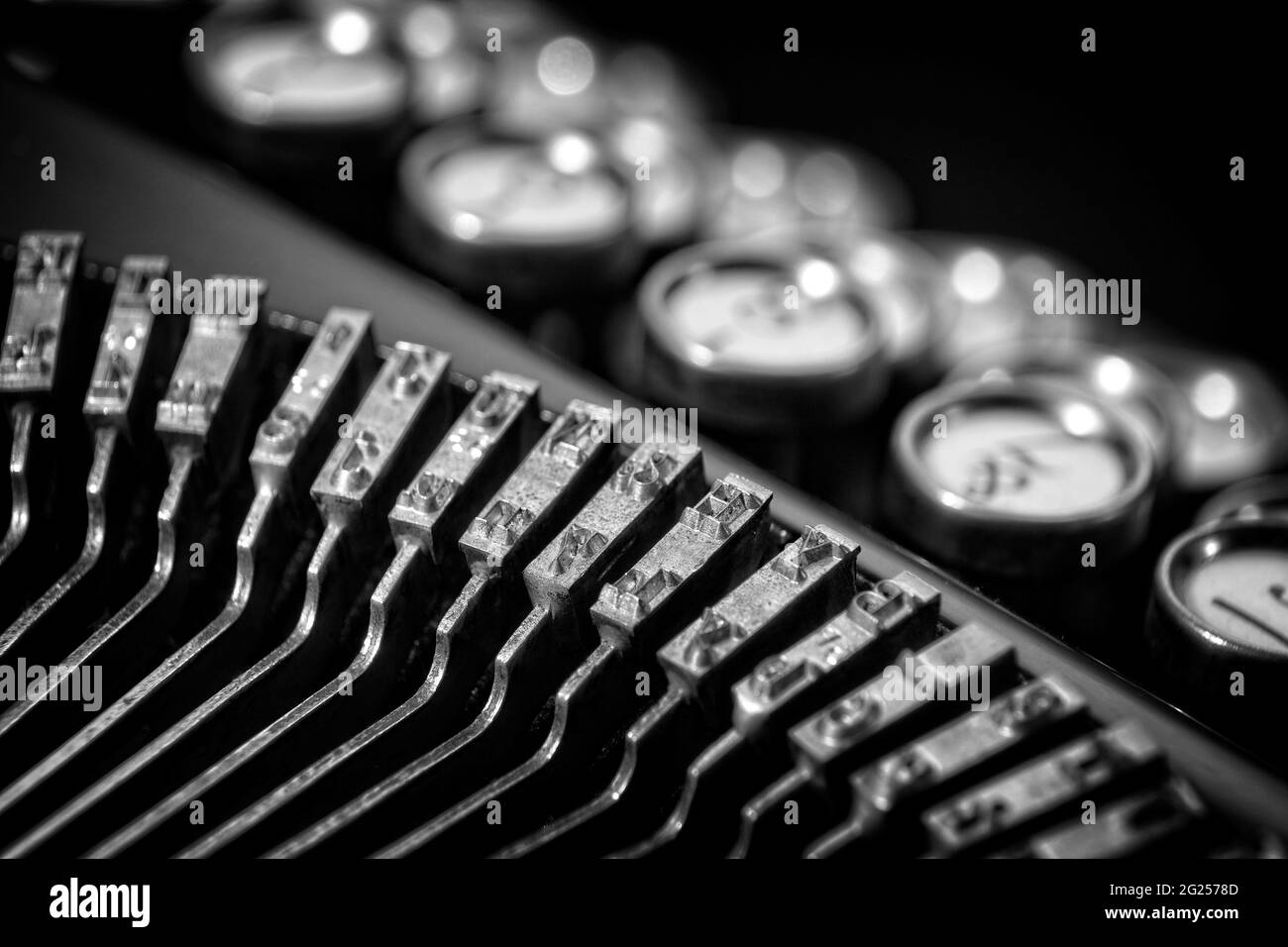 Vintage keyboarding on a classic 1920's typewriter with bokeh keyboard and black background. Suitable for business offices and hotel rooms or lobbies. Stock Photo