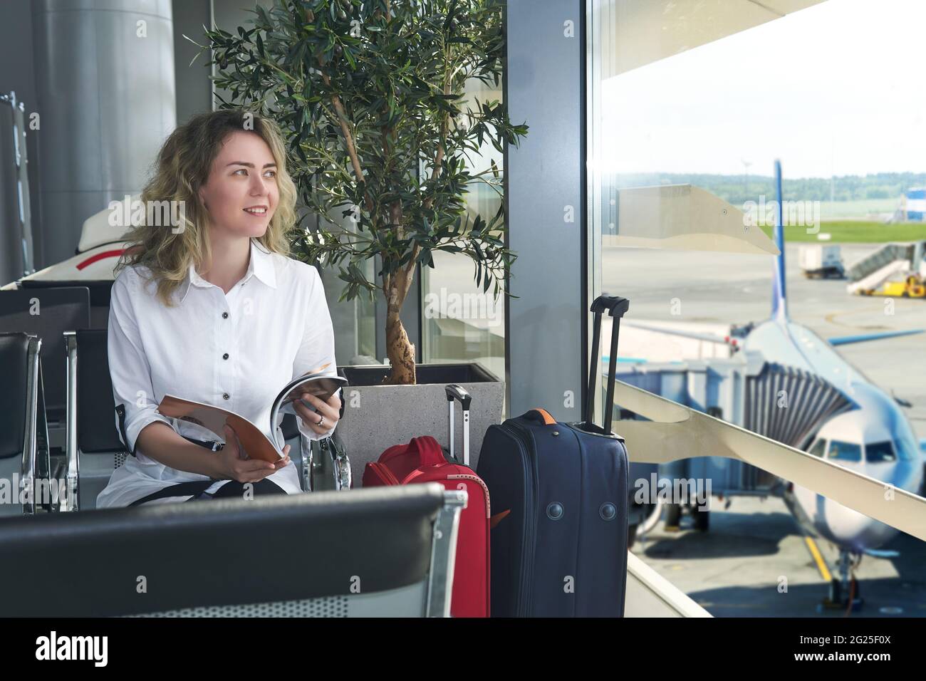 happy woman traveler in waiting room waiting for boarding Stock Photo