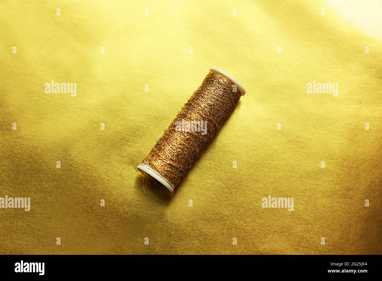 Sewing gold threads on a gold background. Bright shiny threads
