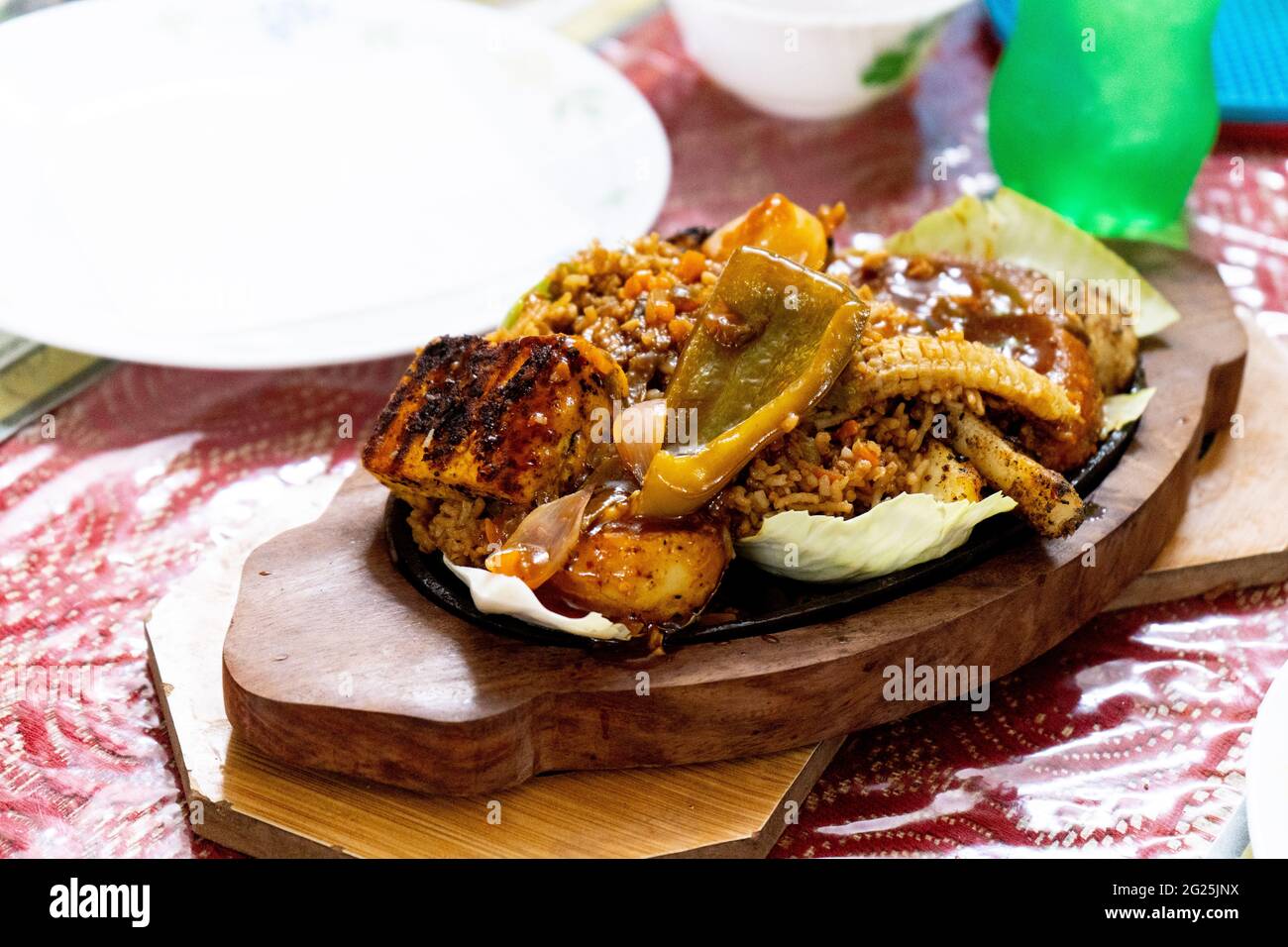 https://c8.alamy.com/comp/2G25JNX/smoking-sizzler-shot-with-vegetables-meat-chicken-cabbage-and-chilis-placed-on-iron-hot-plate-and-served-on-a-wooden-tray-2G25JNX.jpg
