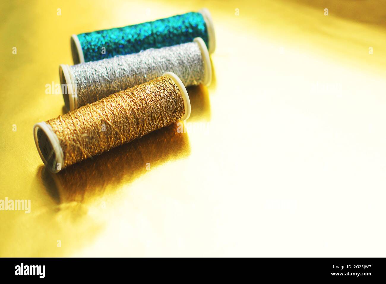 Sewing threads on a gold background. Bright shiny threads. Gold and