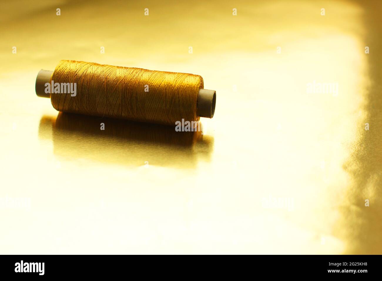 Sewing gold threads on a gold background. Bright shiny threads