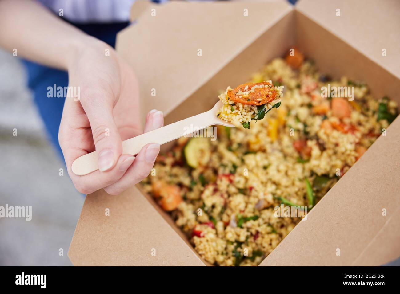 Close Up Of Woman Eating Healthy Vegan Or Vegetarian Takeaway Lunch From Recyclable Packaging With Wooden Fork Stock Photo