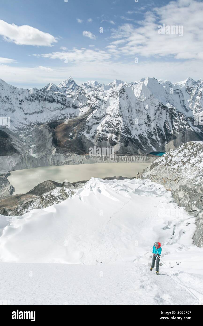 Climber in big mountain landscape with blue skies and glacier lake Stock Photo