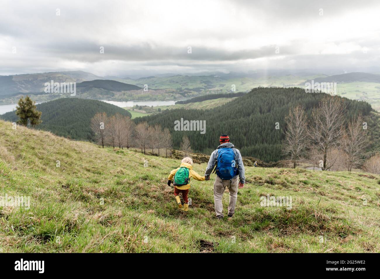 Child and dad walking together in New Zealand hillside Stock Photo