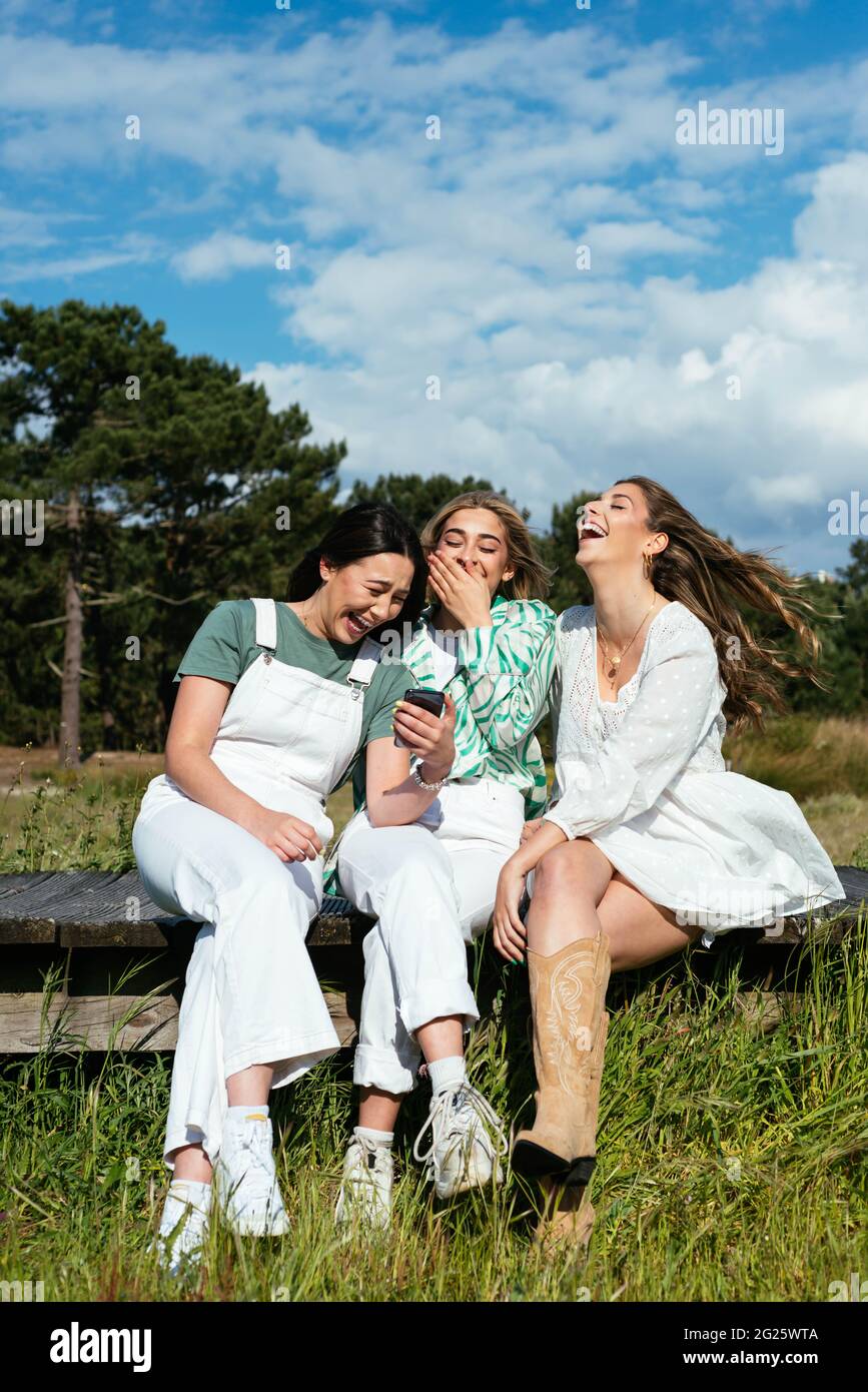 Three female friends using mobile phone and having fun Stock Photo