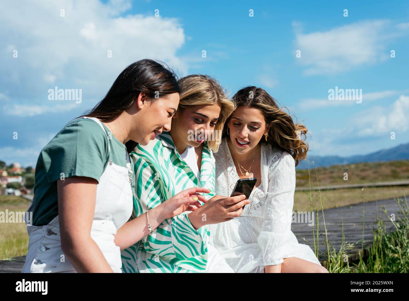 Three female friends using mobile phone and having fun Stock Photo