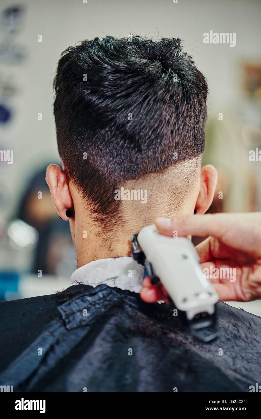 A hairdresser cuts the hair of a young boy with an electric machine Stock Photo