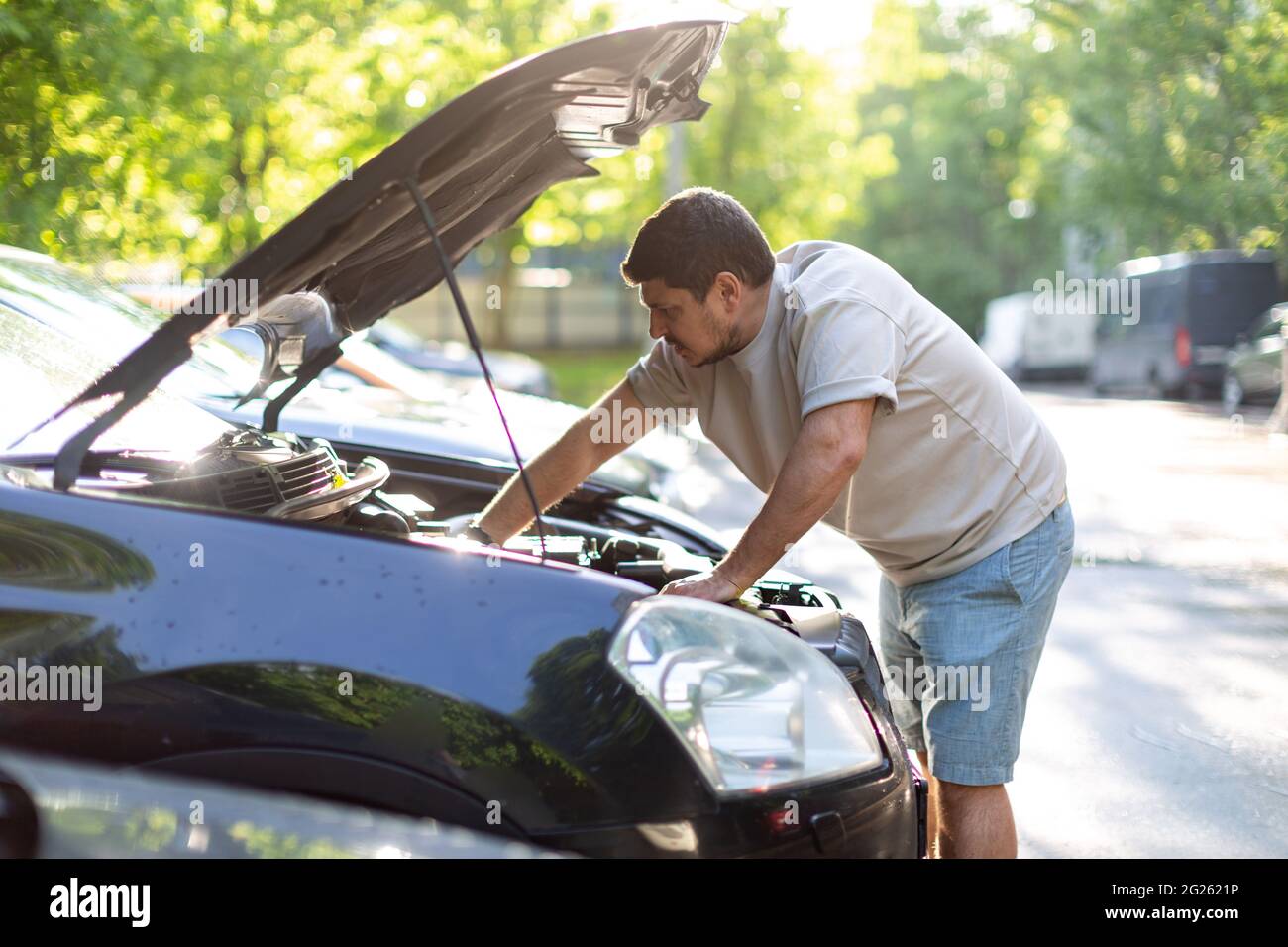 a man on a city street checks the operation of the car, looks under th Stock Photo