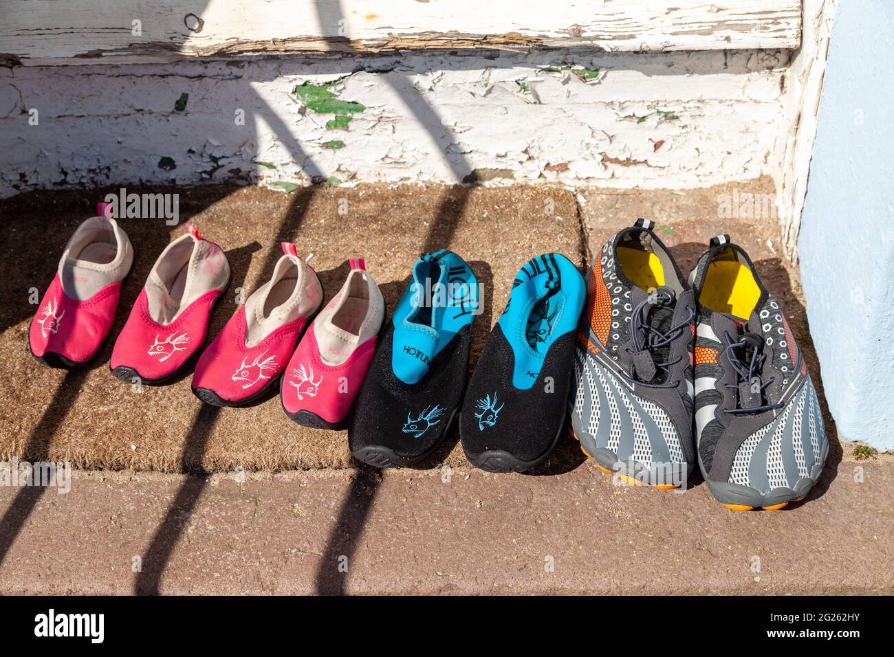 Family's beach shoes by door step Stock Photo