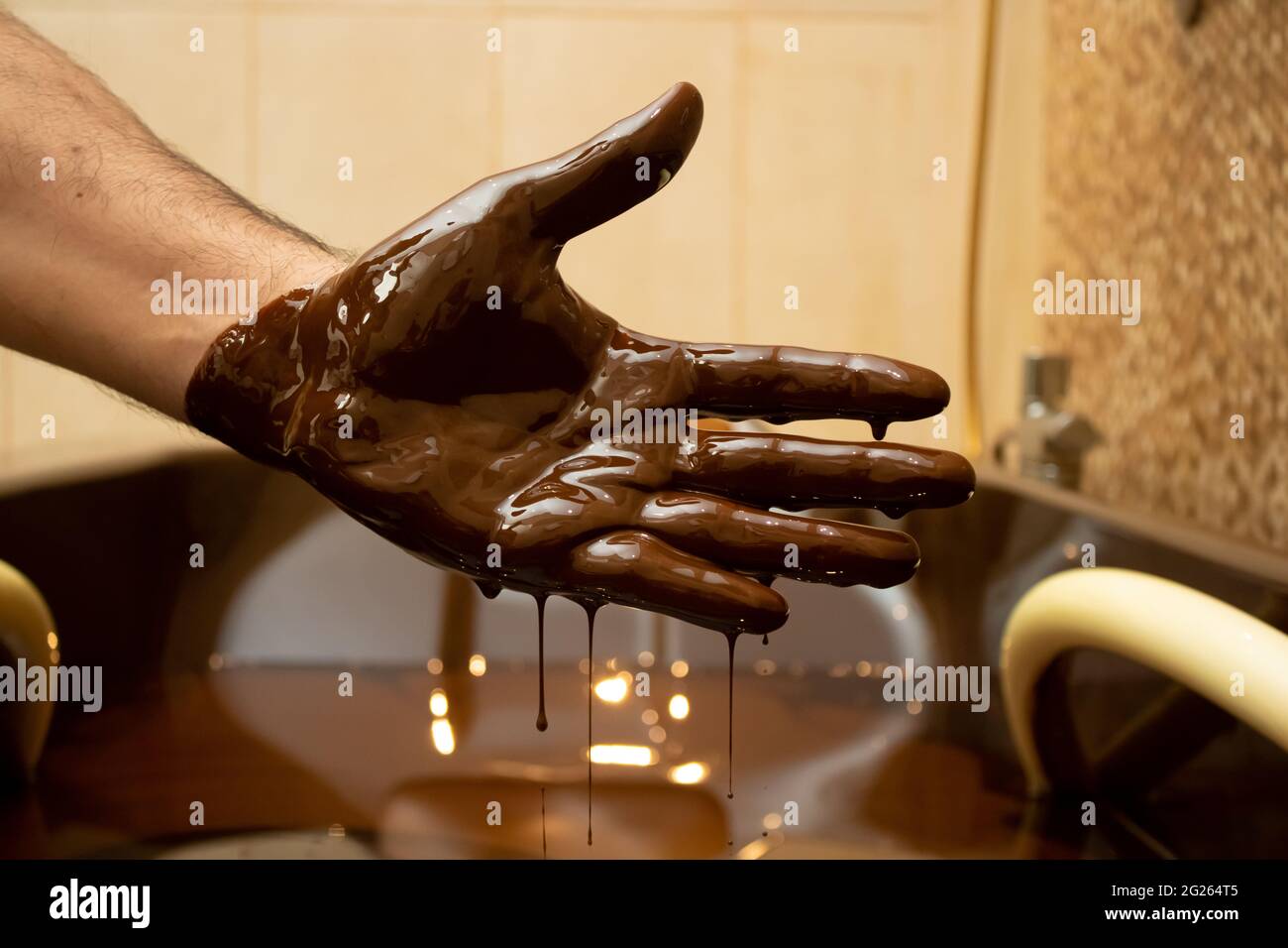 Closeup shot of a male hand covered with dark brown crude oil Stock Photo