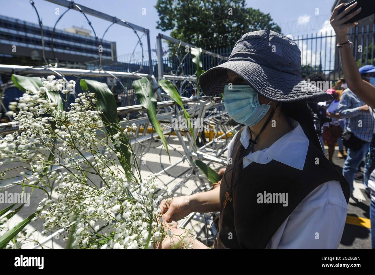 San Salvador, El Salvador. 08th June, 2021. A nun places flowers on a barbed wire fence set by riot control police officers during the demonstration. Members of churches and social movements took to the streets to protest for the environment, the Salvadoran Congress archived hundreds of law protects including several proposal for the environment, including water as a human right. (Photo by Camilo Freedman/SOPA Images/Sipa USA) Credit: Sipa USA/Alamy Live News Stock Photo