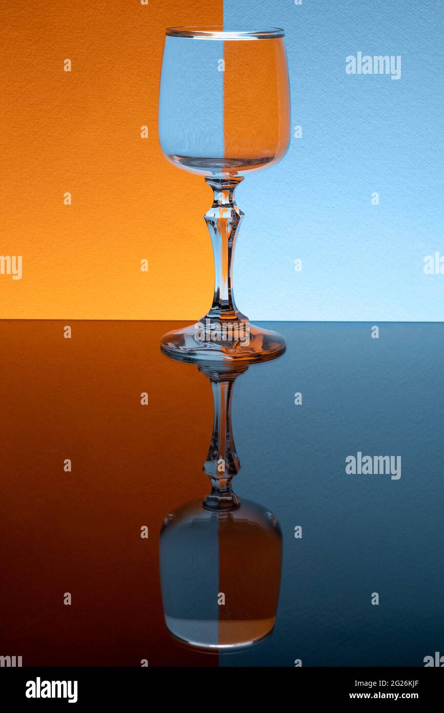 Glass of water on blue and orange background. Mirror reflection table. Creative orange blue background Stock Photo