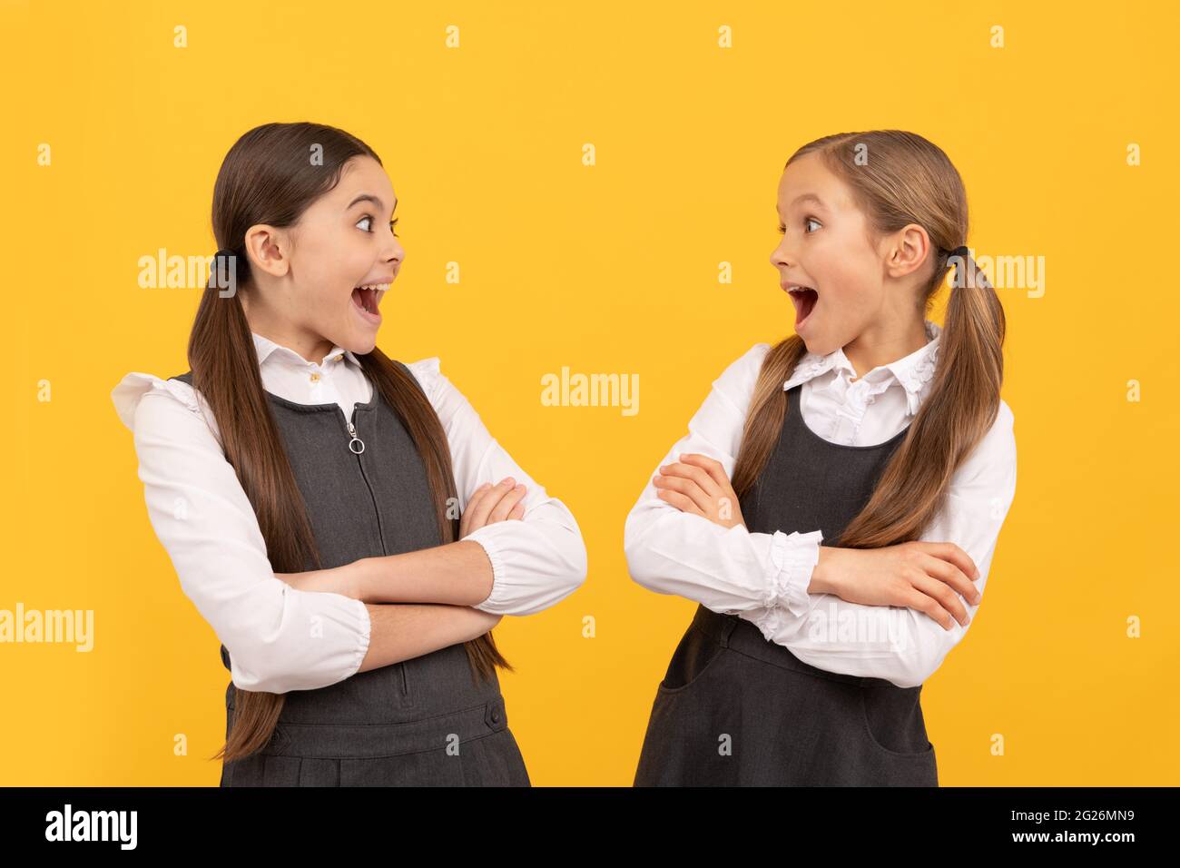 Surprised little kids look at each other with open mouths in formal school uniforms, surprise Stock Photo
