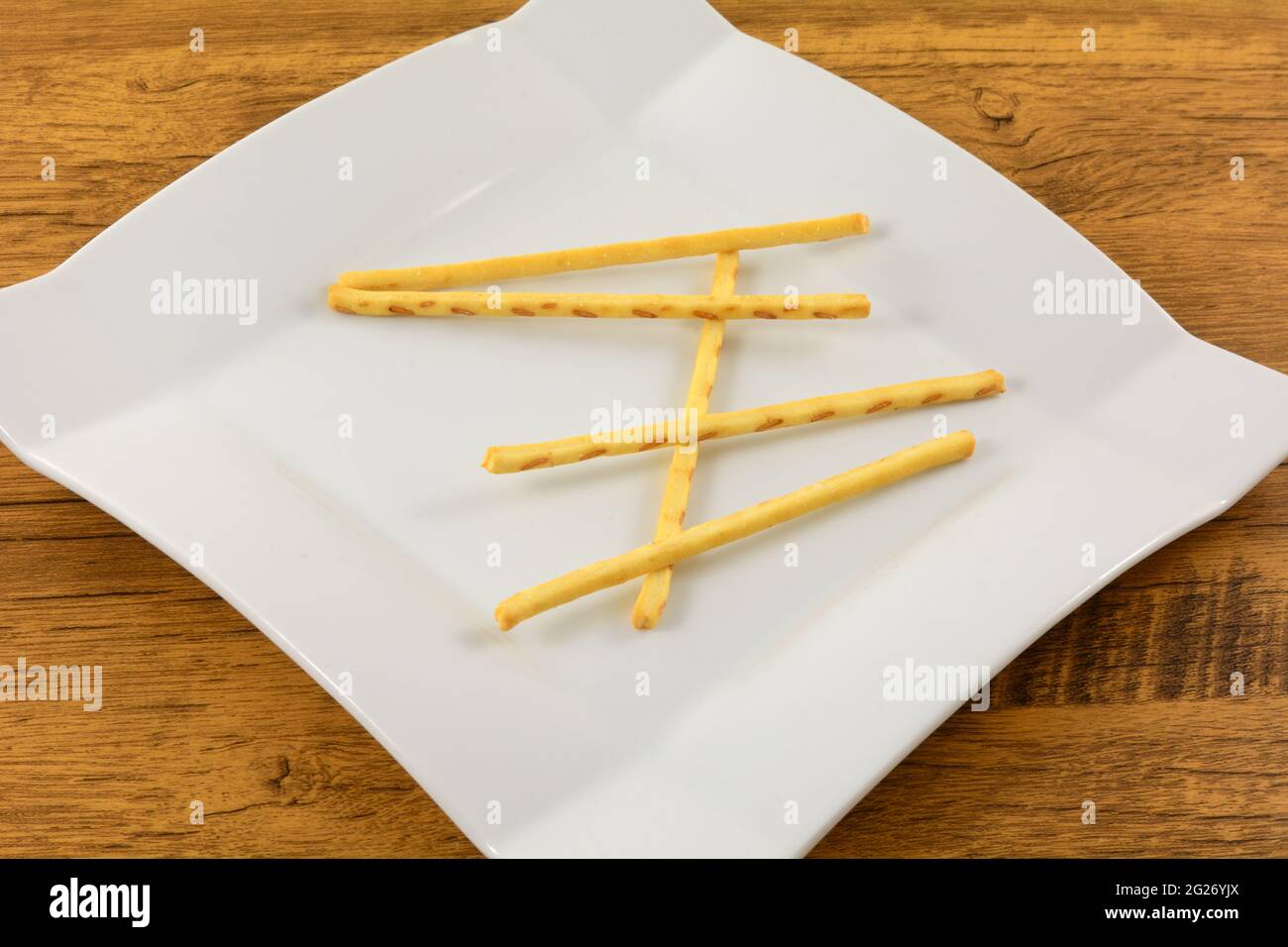 Buttered corn flavored pretzel sticks on white snack plate on table Stock Photo